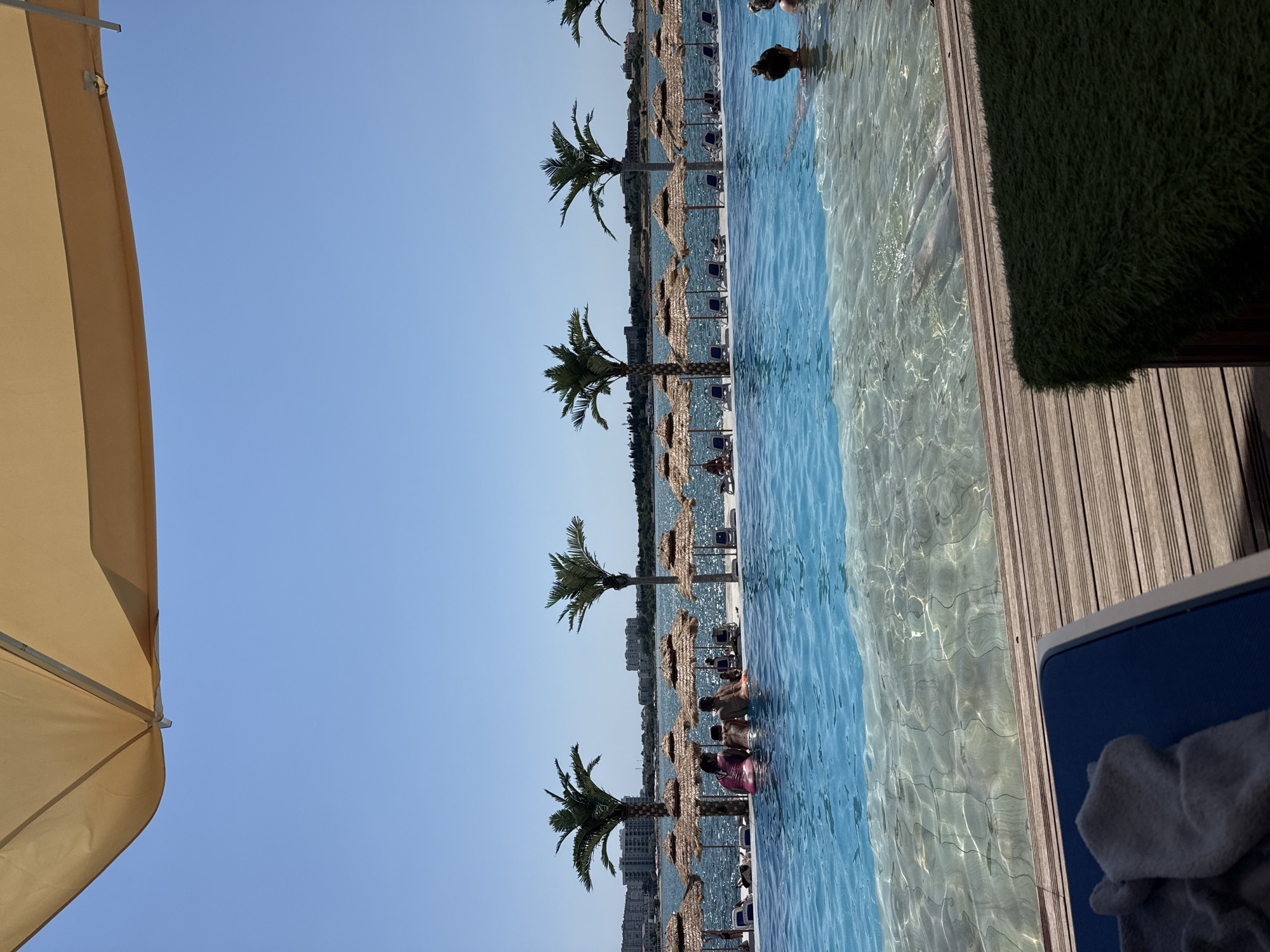 Infinity pool and beach lounges at a sunny coastal resort