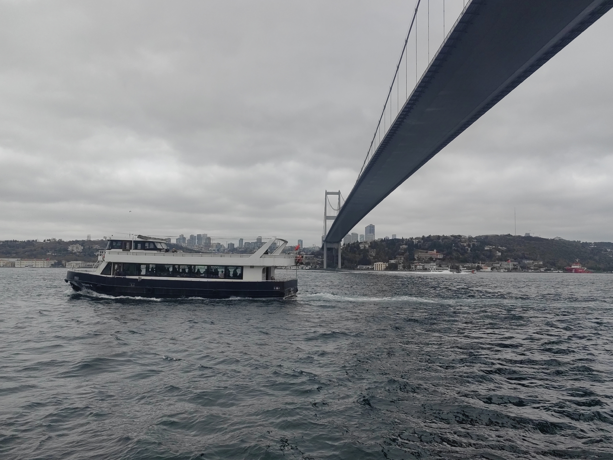 Passenger ferry crosses Bosphorus Strait in Istanbul during overcast morning