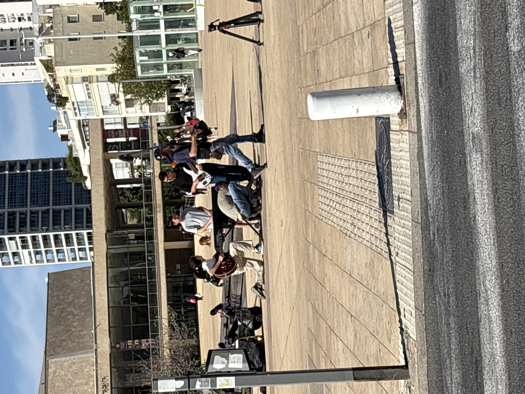 Street musicians perform in Tel Aviv plaza during sunny afternoon