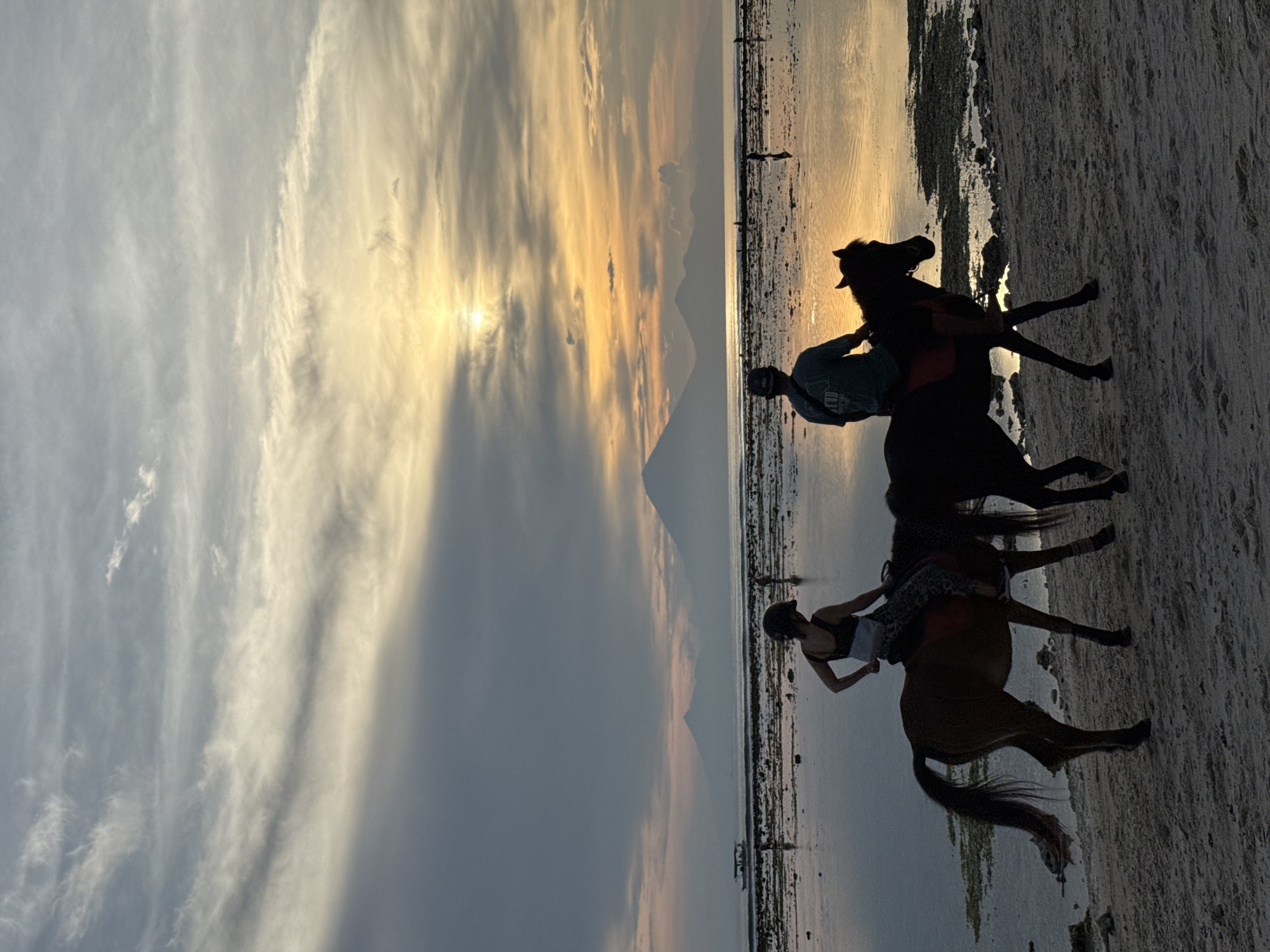 Two horseback riders captured on Indonesian beach at sunset