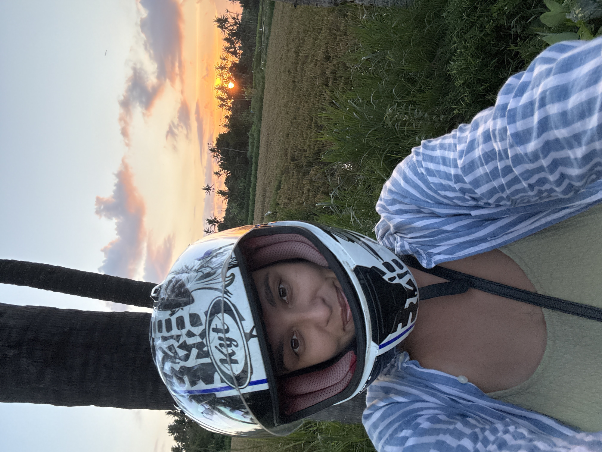 Motorcyclist poses during scenic sunset in Pering rice fields