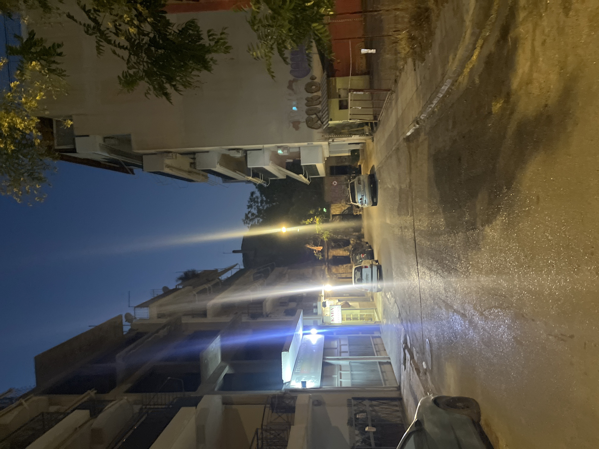 Athens streets at dusk after rain, tram tracks and café terraces