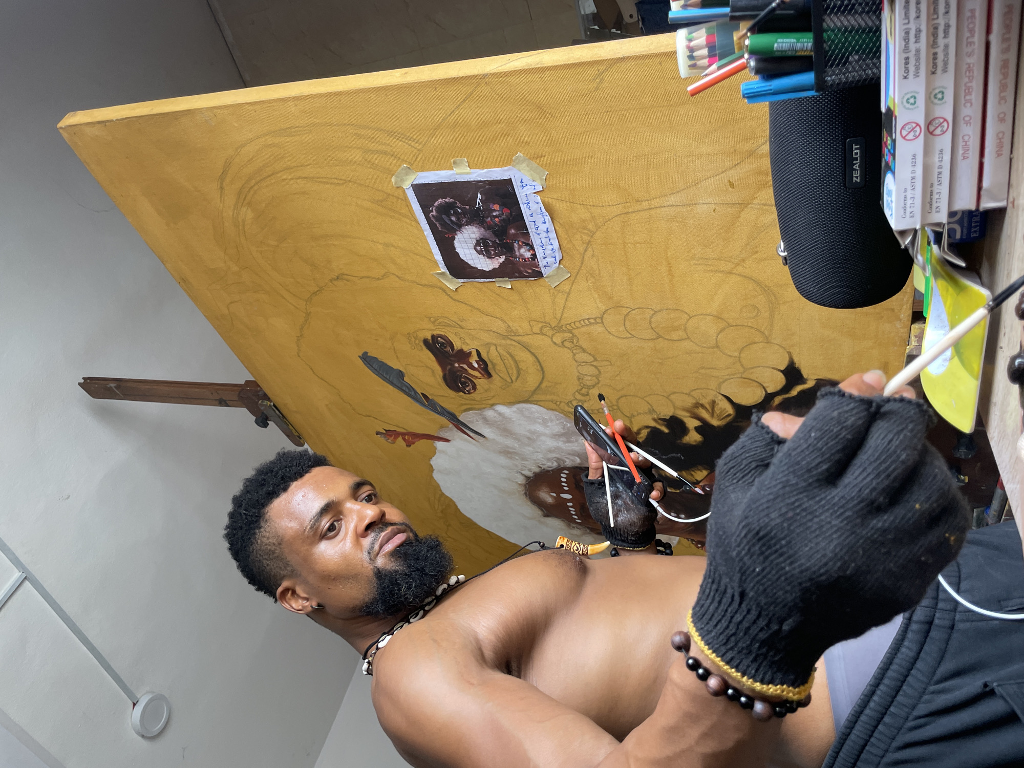 Artist captured working in studio wearing traditional beads in Ado