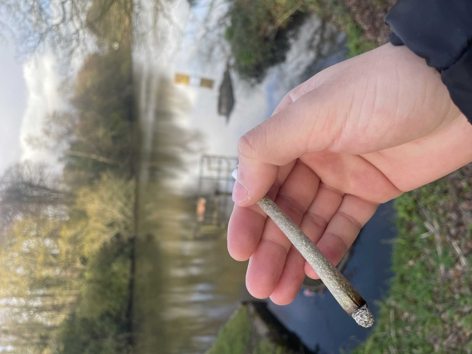 Person smokes marijuana joint by waterway in Salford