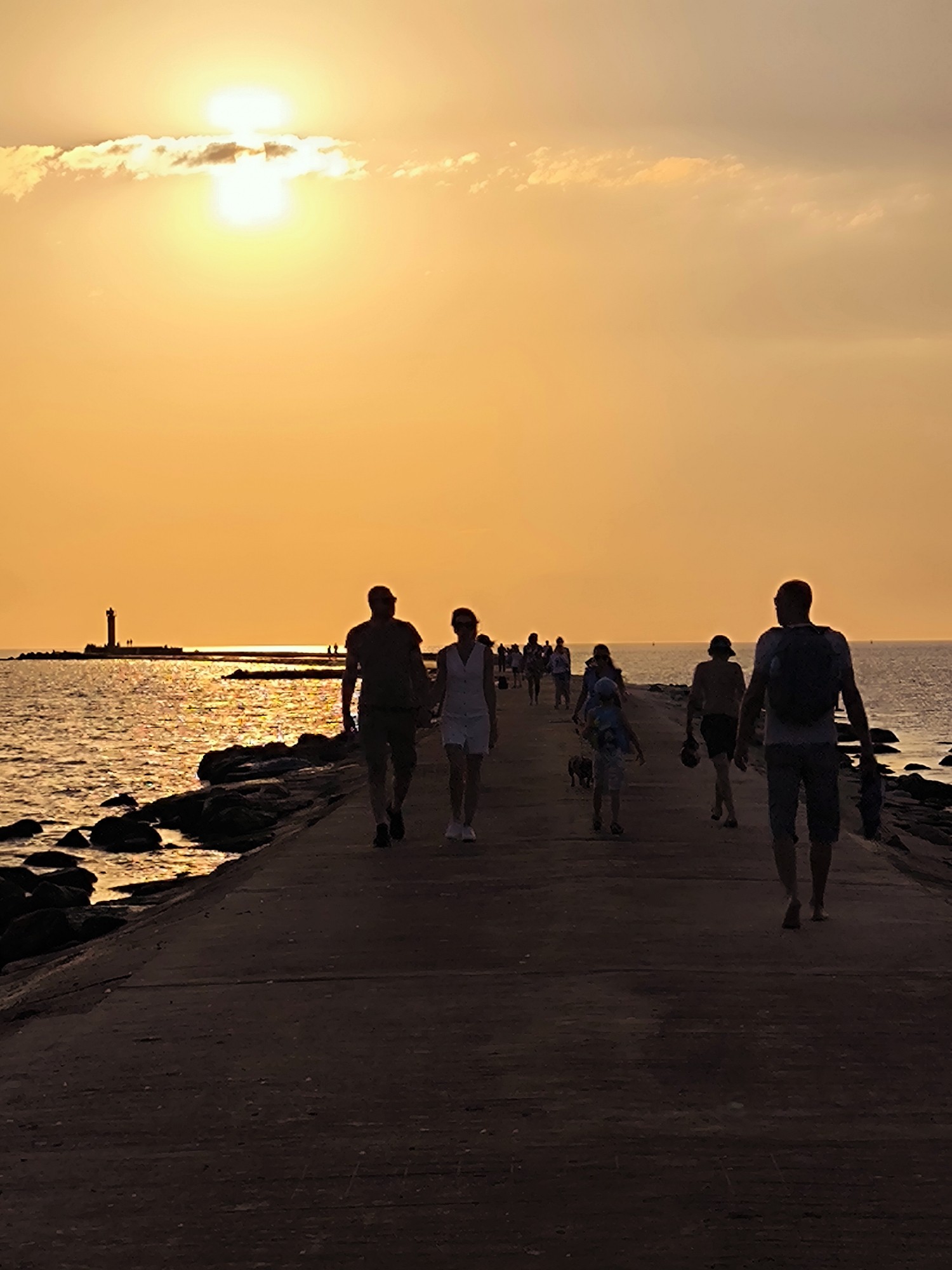 Golden hour on a Riga pier, sailboats and silhouettes at sunset