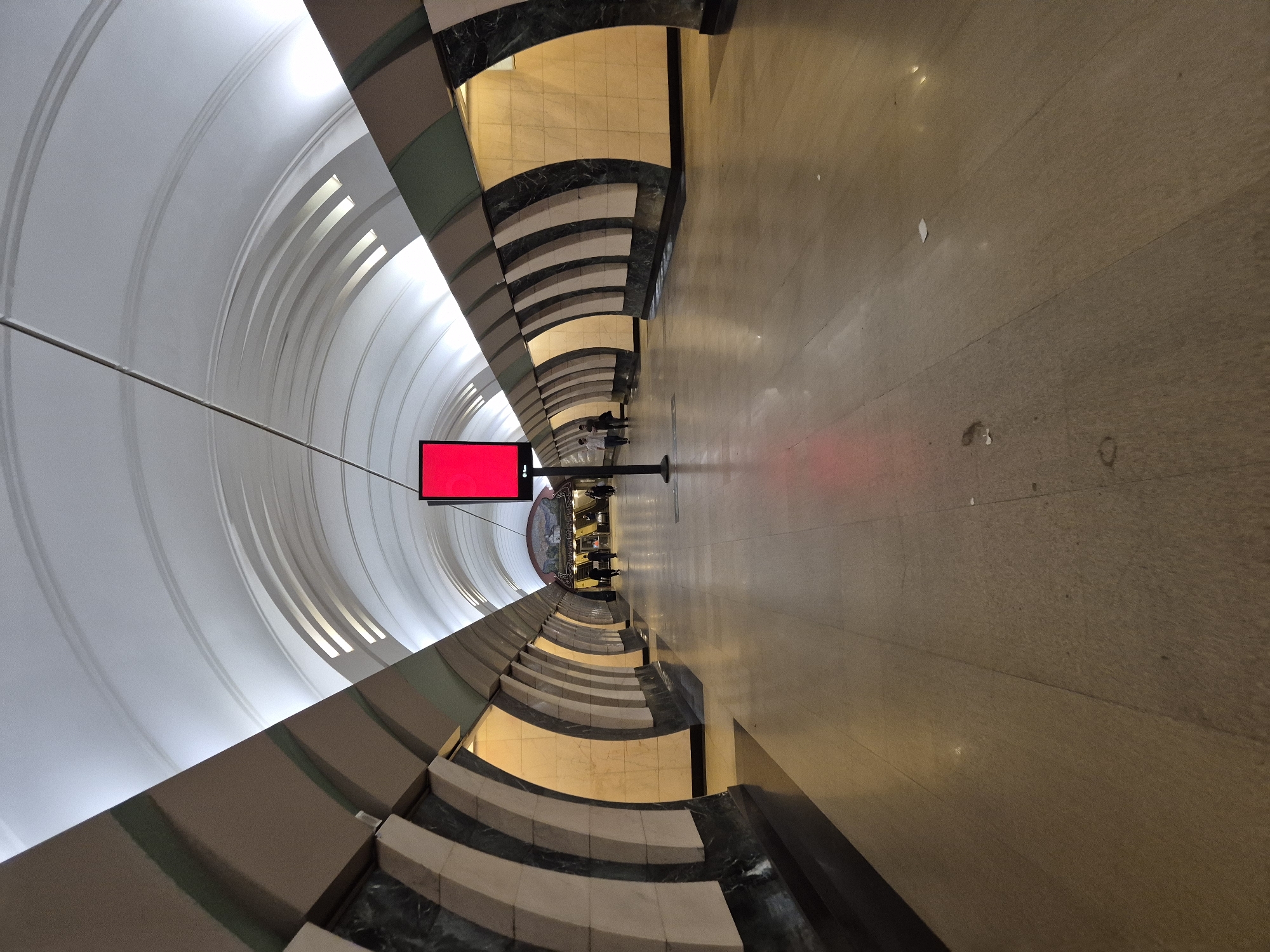 Subway platform with curved ceiling and red digital ad screen