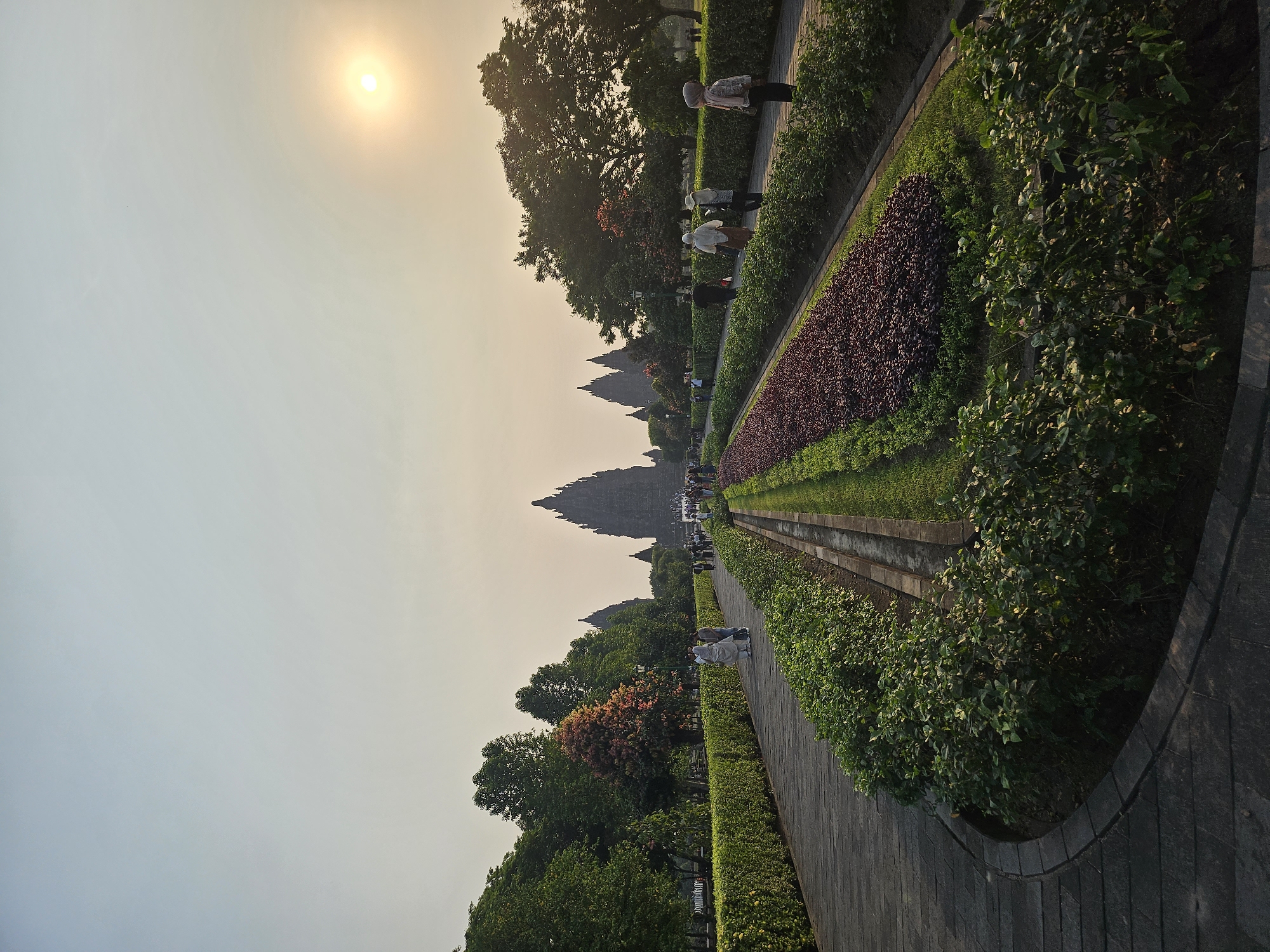 Prambanan Temple at sunset, bathed in hazy golden light.