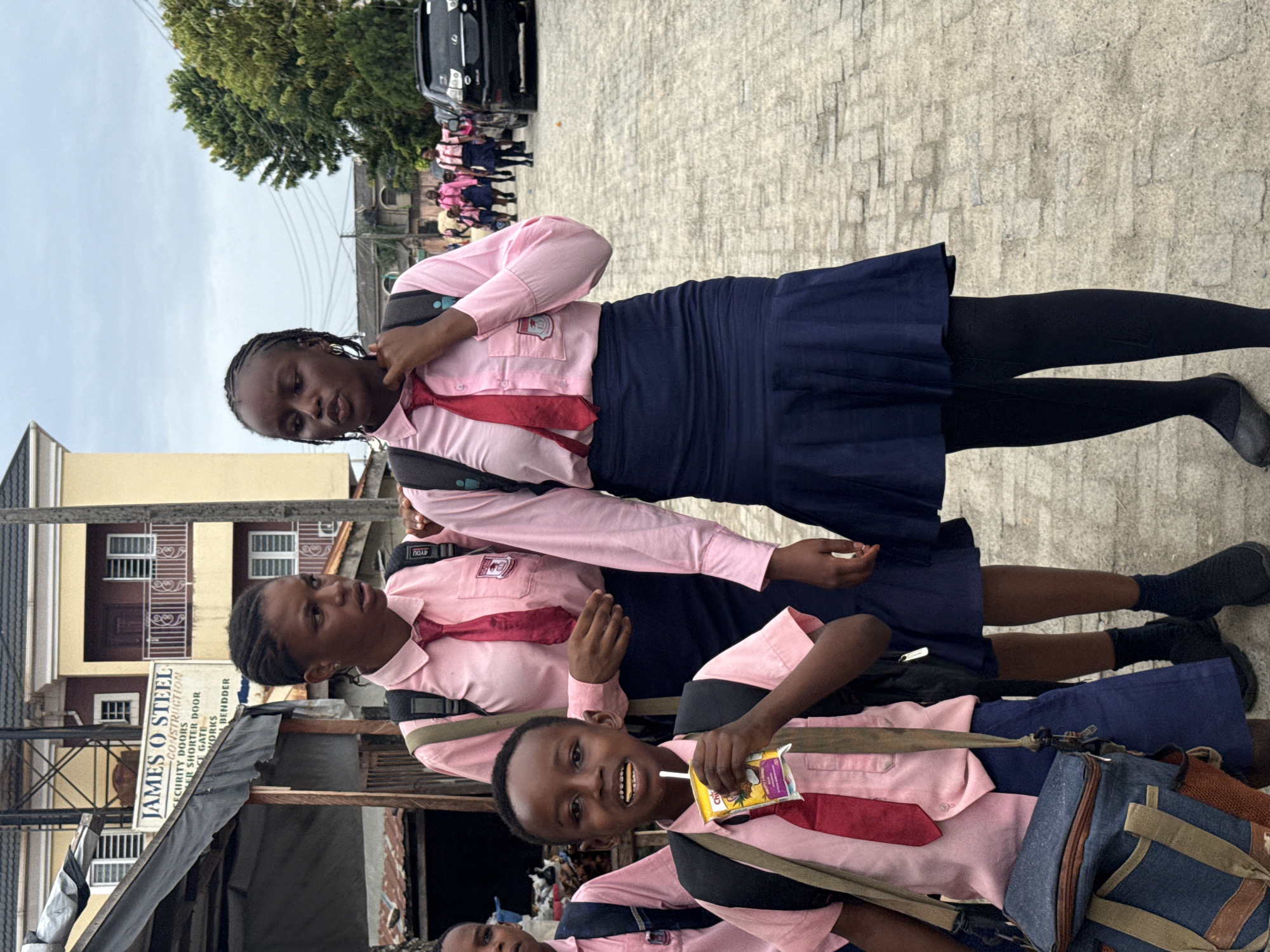 School children gather on street near business in Ado