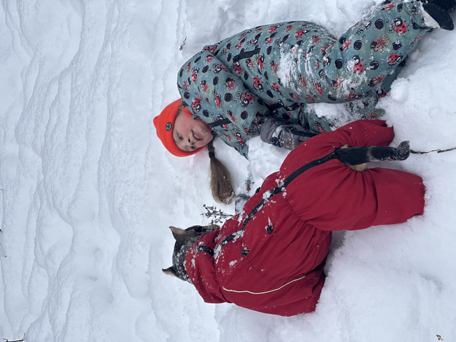Child and dog play in snowy Saint Petersburg park