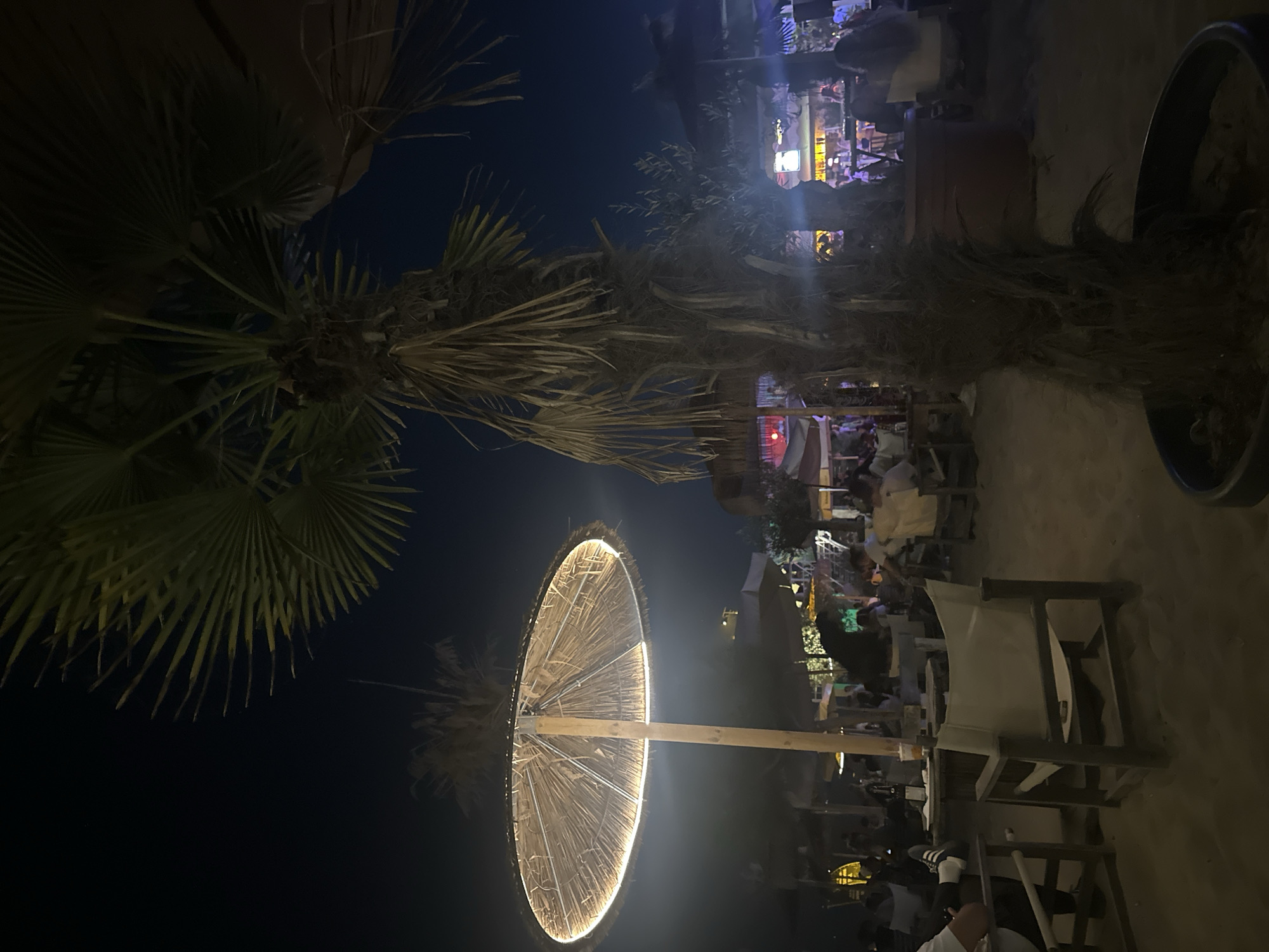 Nighttime hang at a beach bar with art and crowds