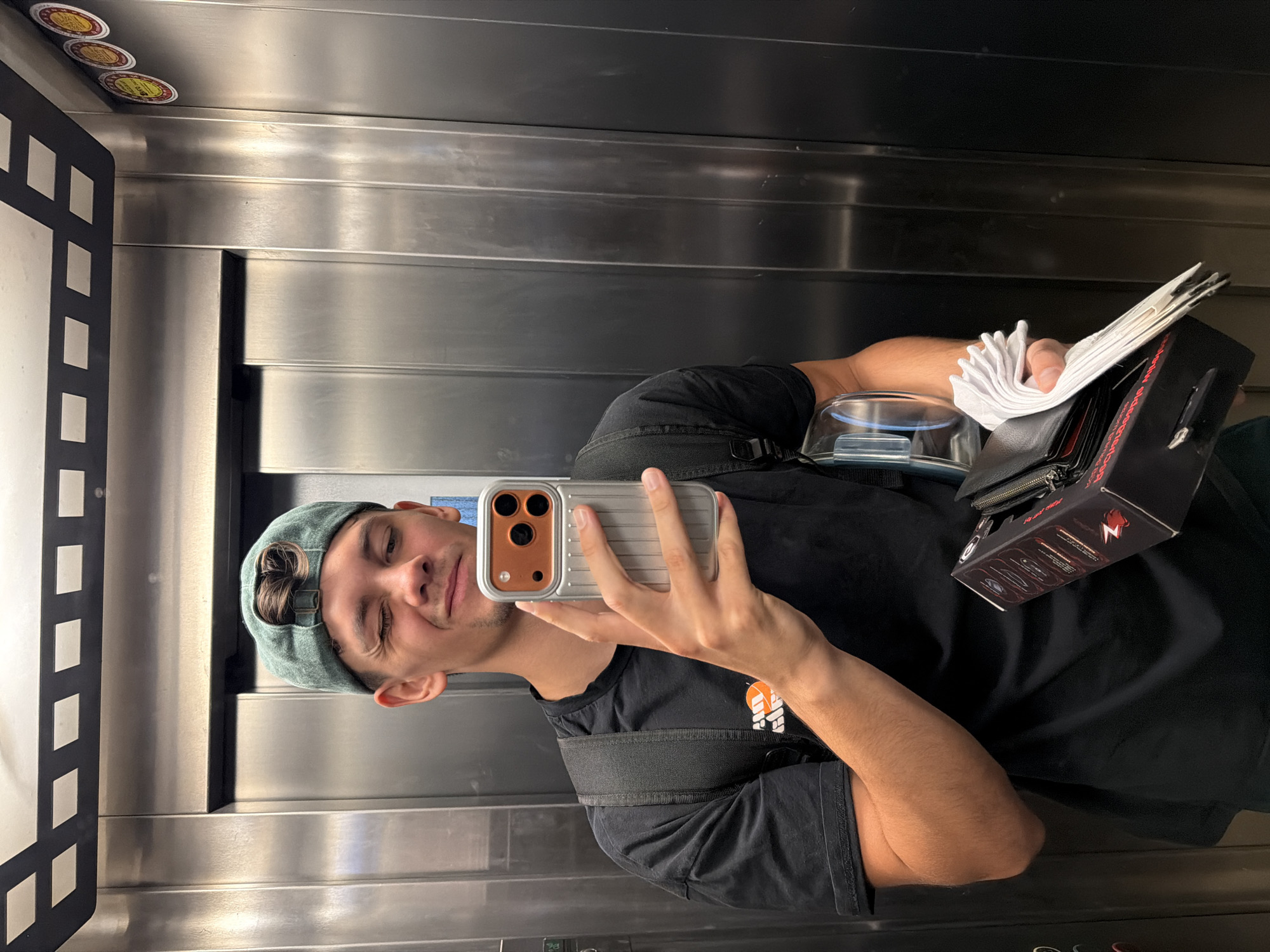 Mirror selfie in a Blagoevgrad elevator, green cap and backpack