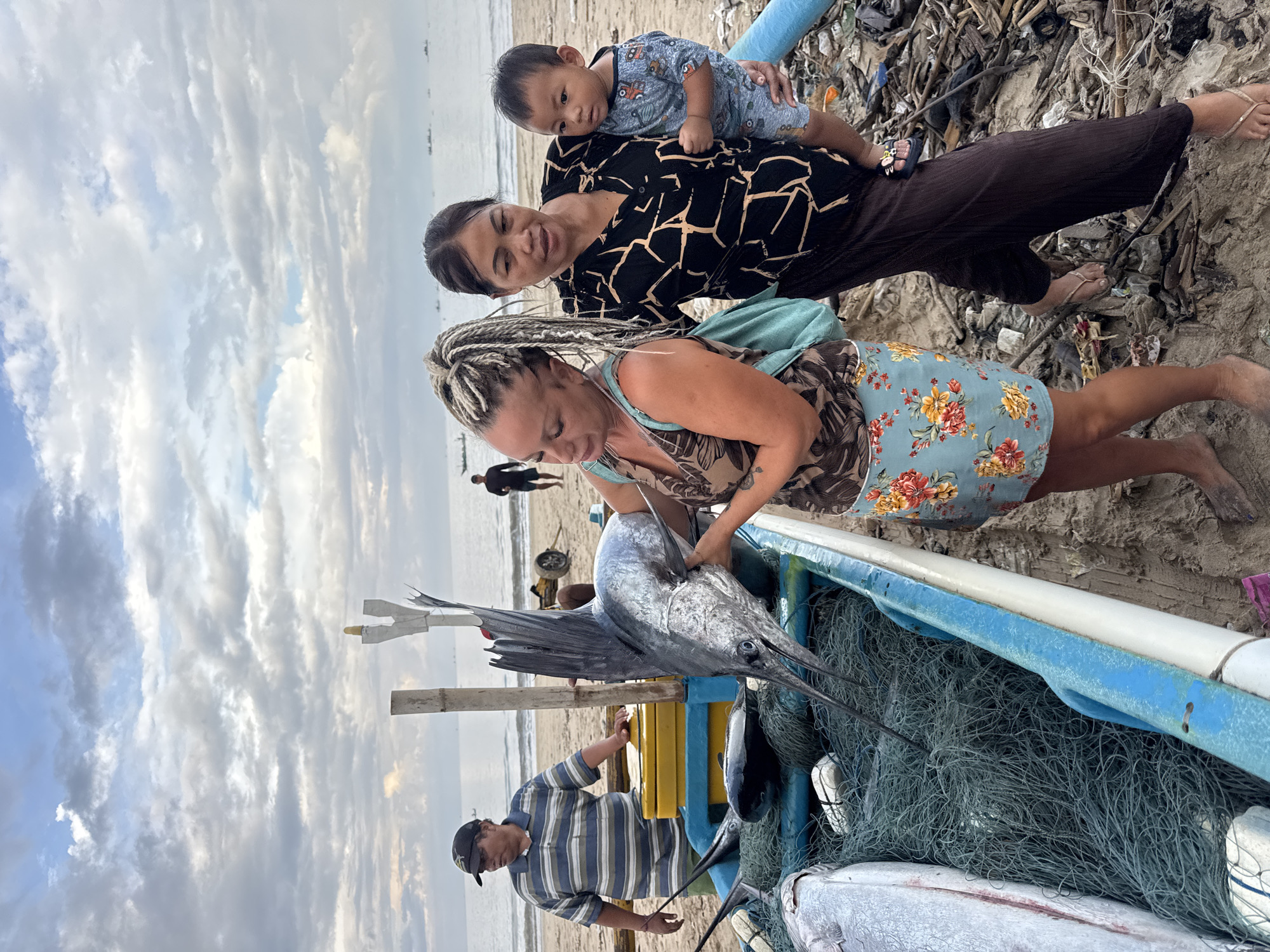 Woman examines large marlin catch on Kuta beach