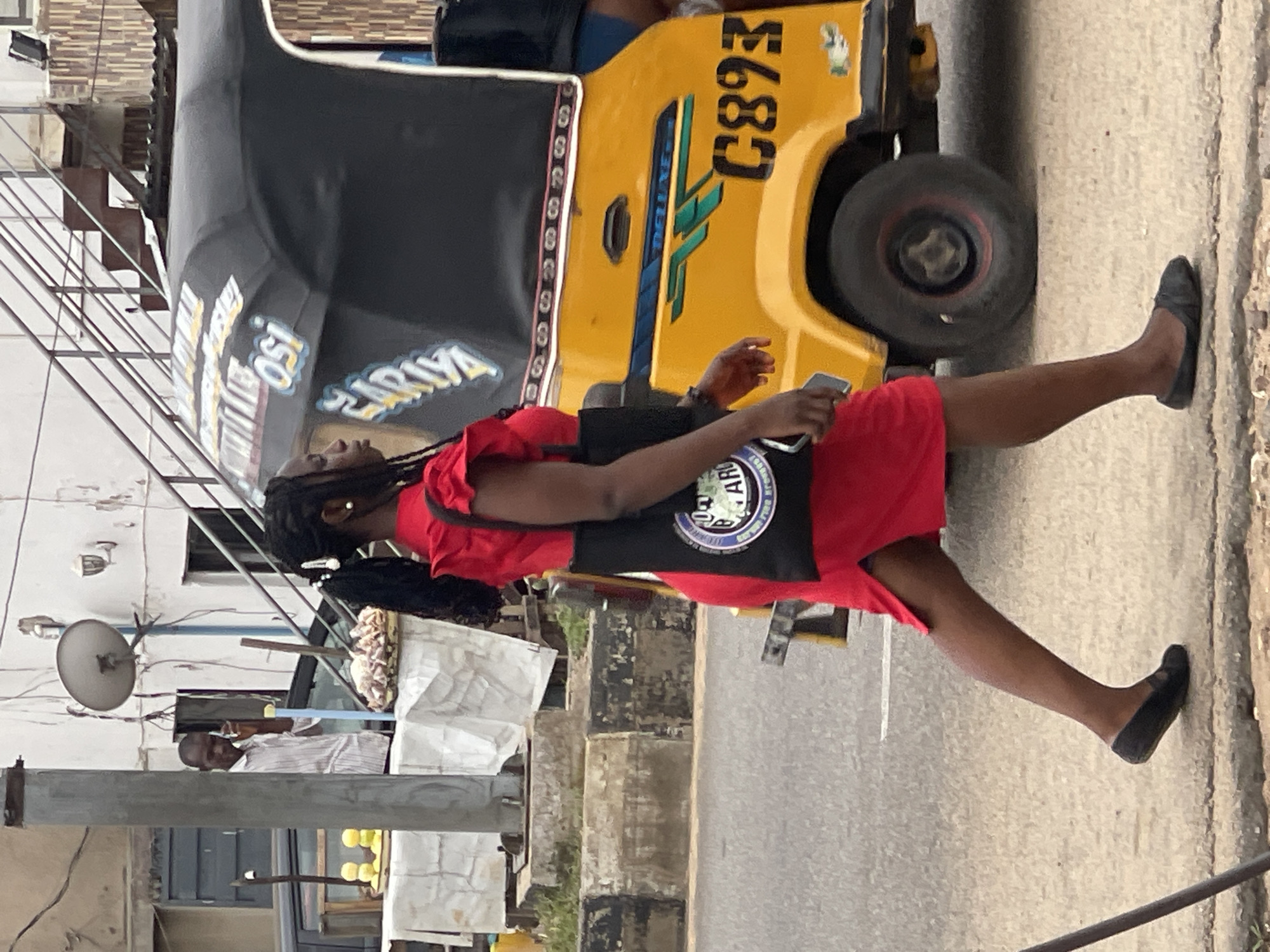 Busy Nigerian street scene with vendors, tuk-tuks, and motorcycles