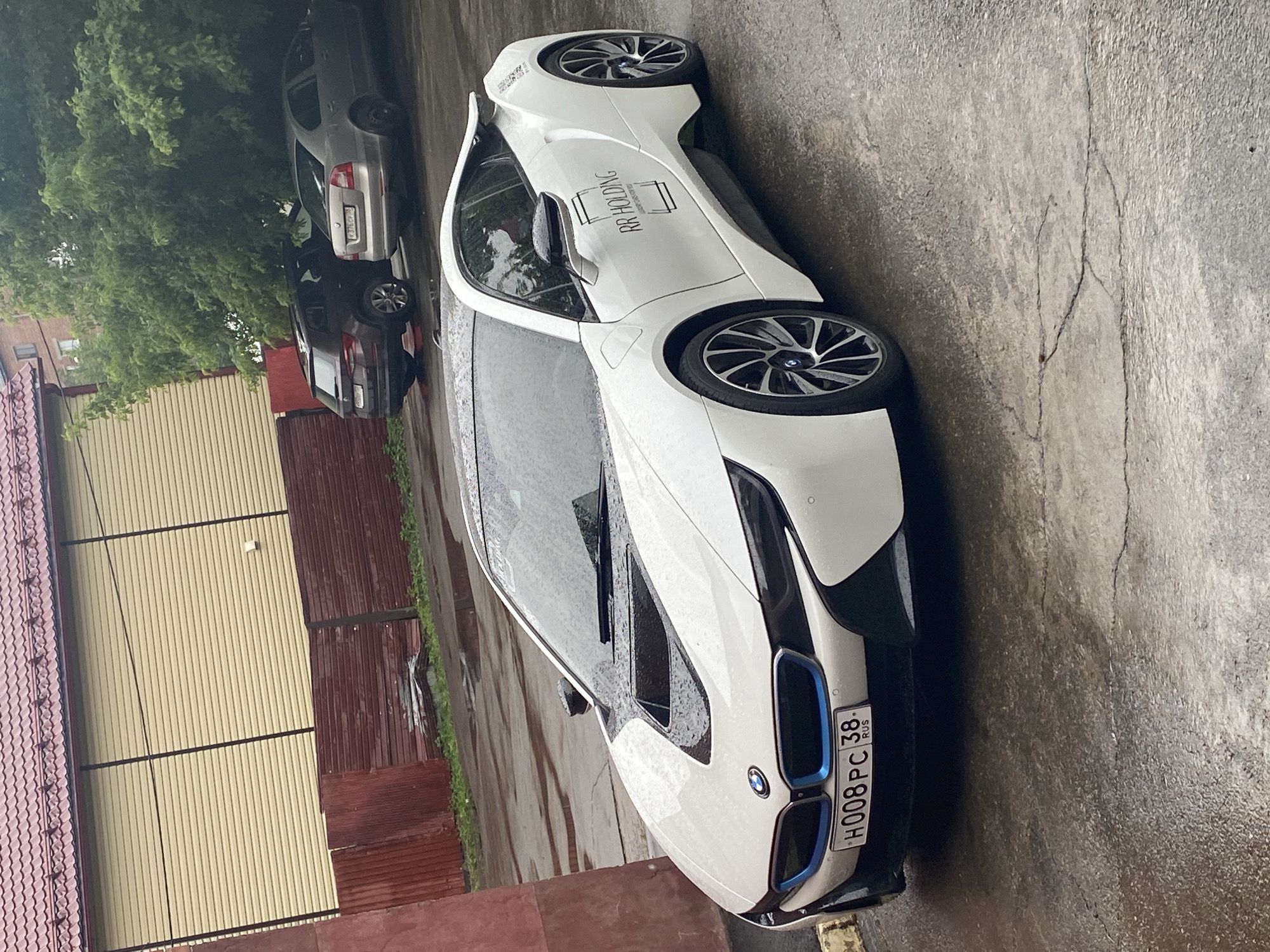White BMW i8 parked on wet asphalt in Irkutsk