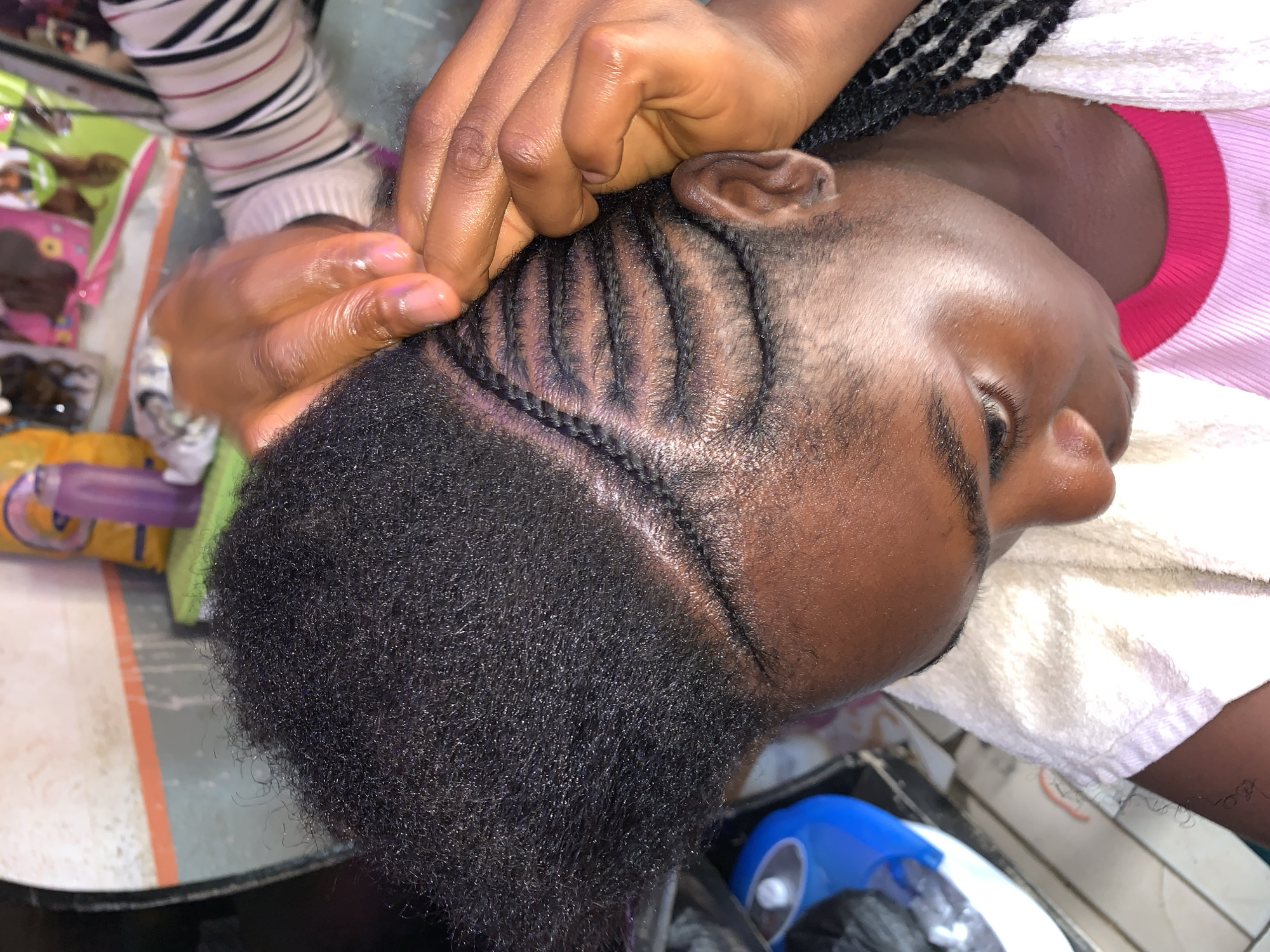 Woman gets cornrow braids at Nigerian salon