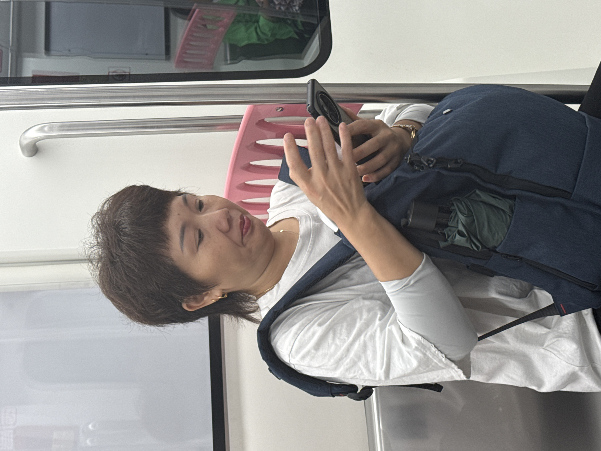 Woman commutes on Longta subway with phone and backpack