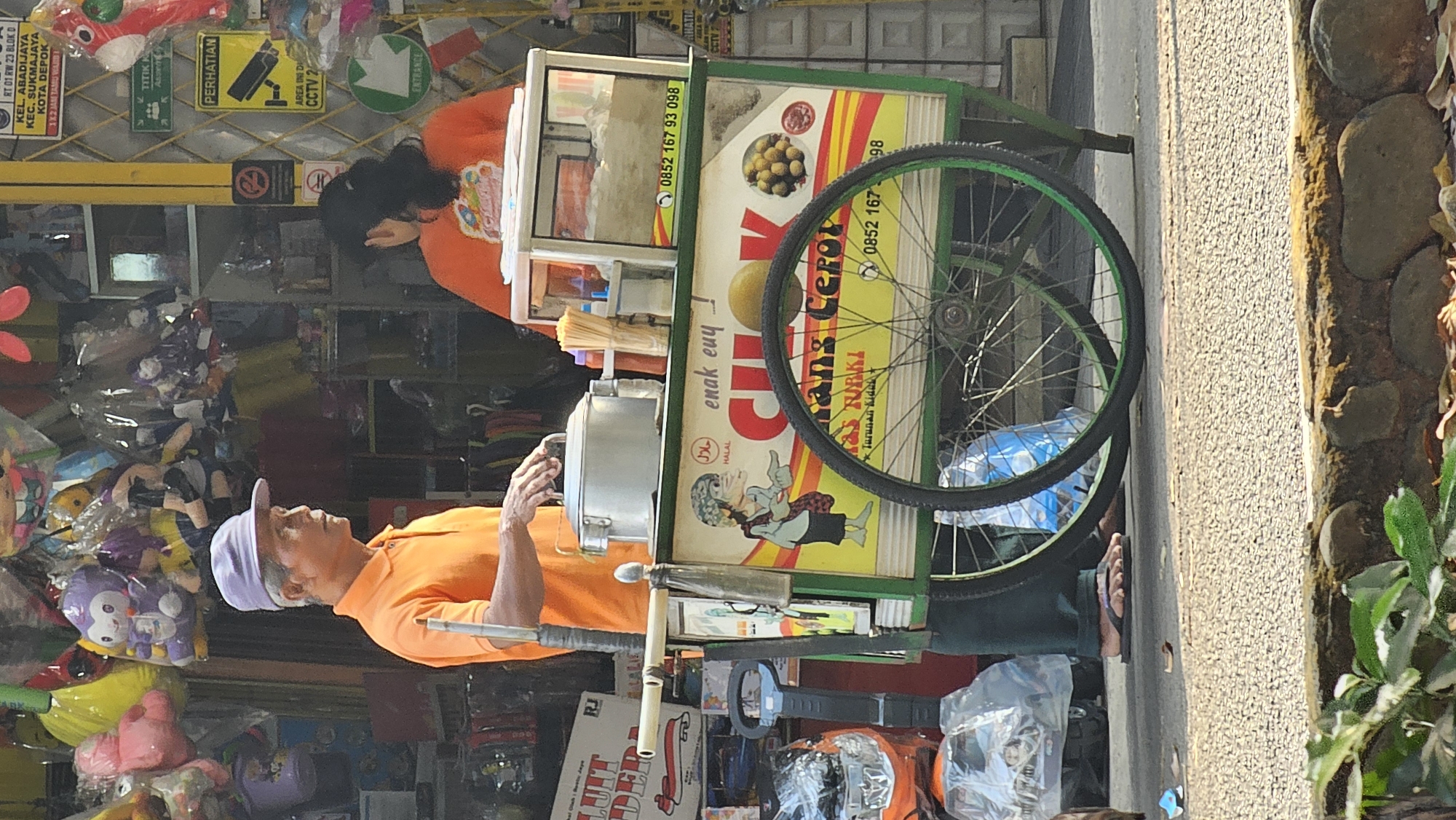 Sanitation worker doing rounds on a commercial street in Depok