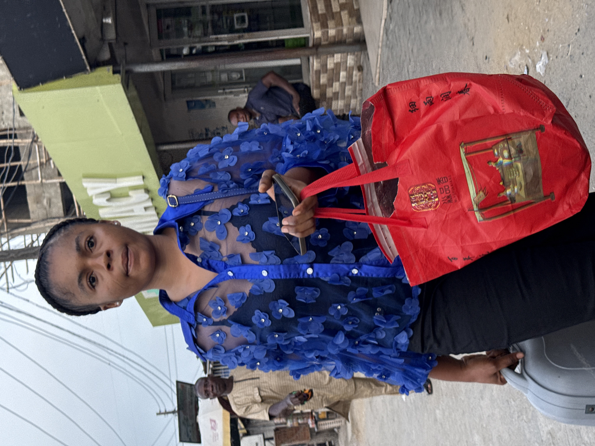 Woman with luggage, shopping bag observed on Ado sidewalk