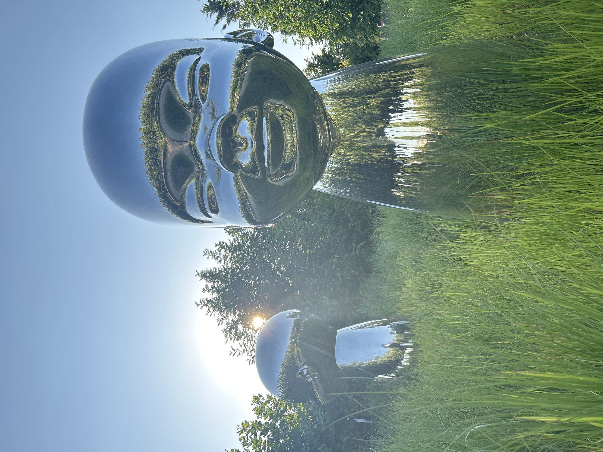 Reflective baby head sculptures in a sunny Krasnodar park