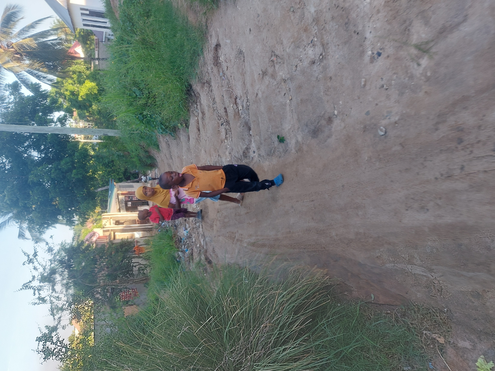 Residents navigate dirt road in Dar es-Salaam neighborhood