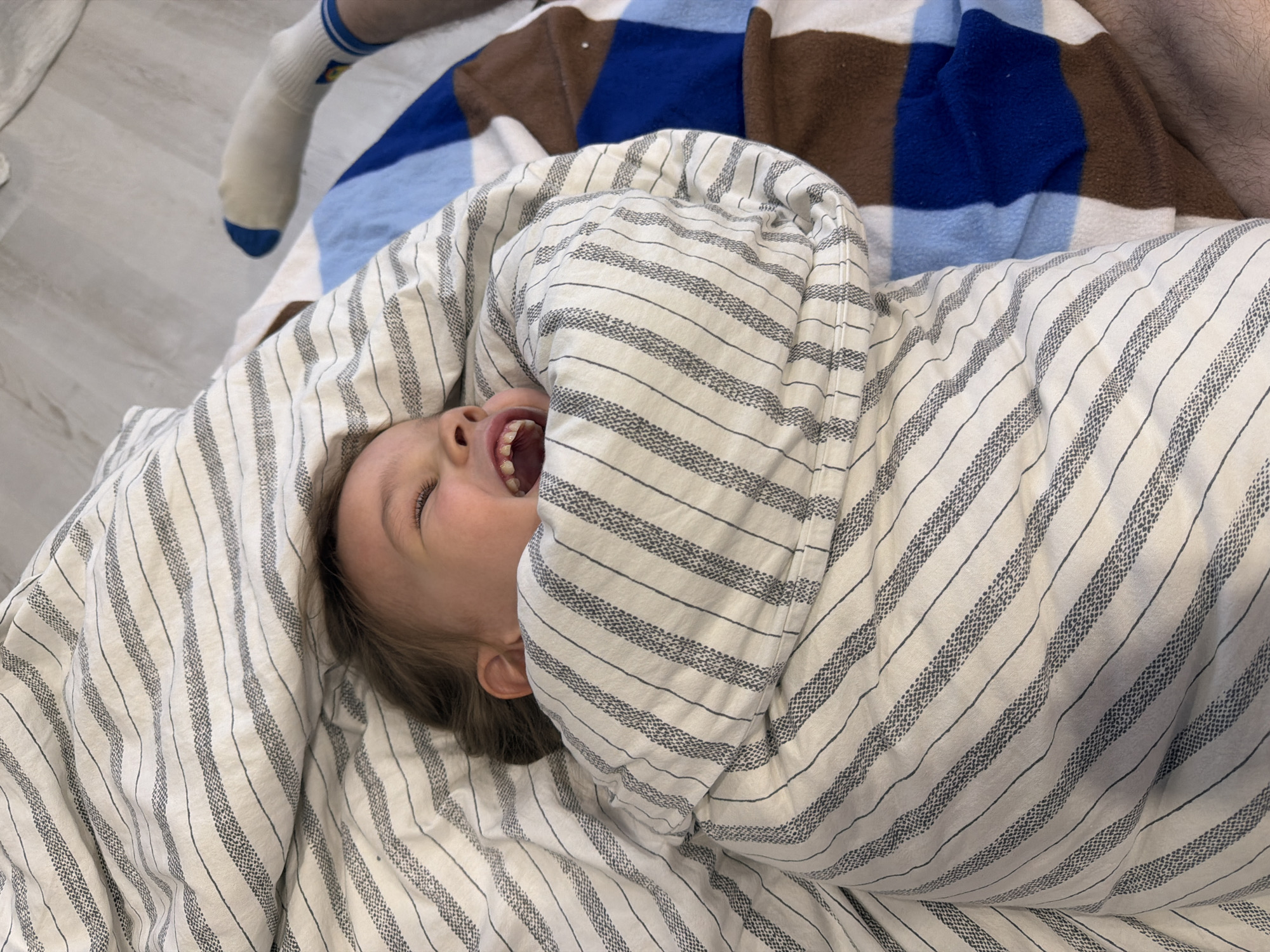 Family shares playful moment on bed in Chaikovsky