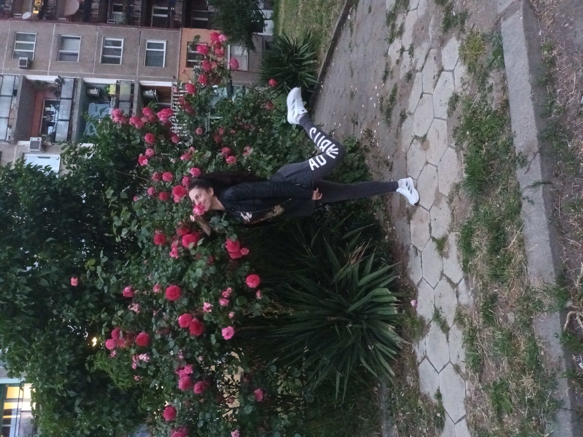Woman performs athletic pose in Adidas gear near flowers