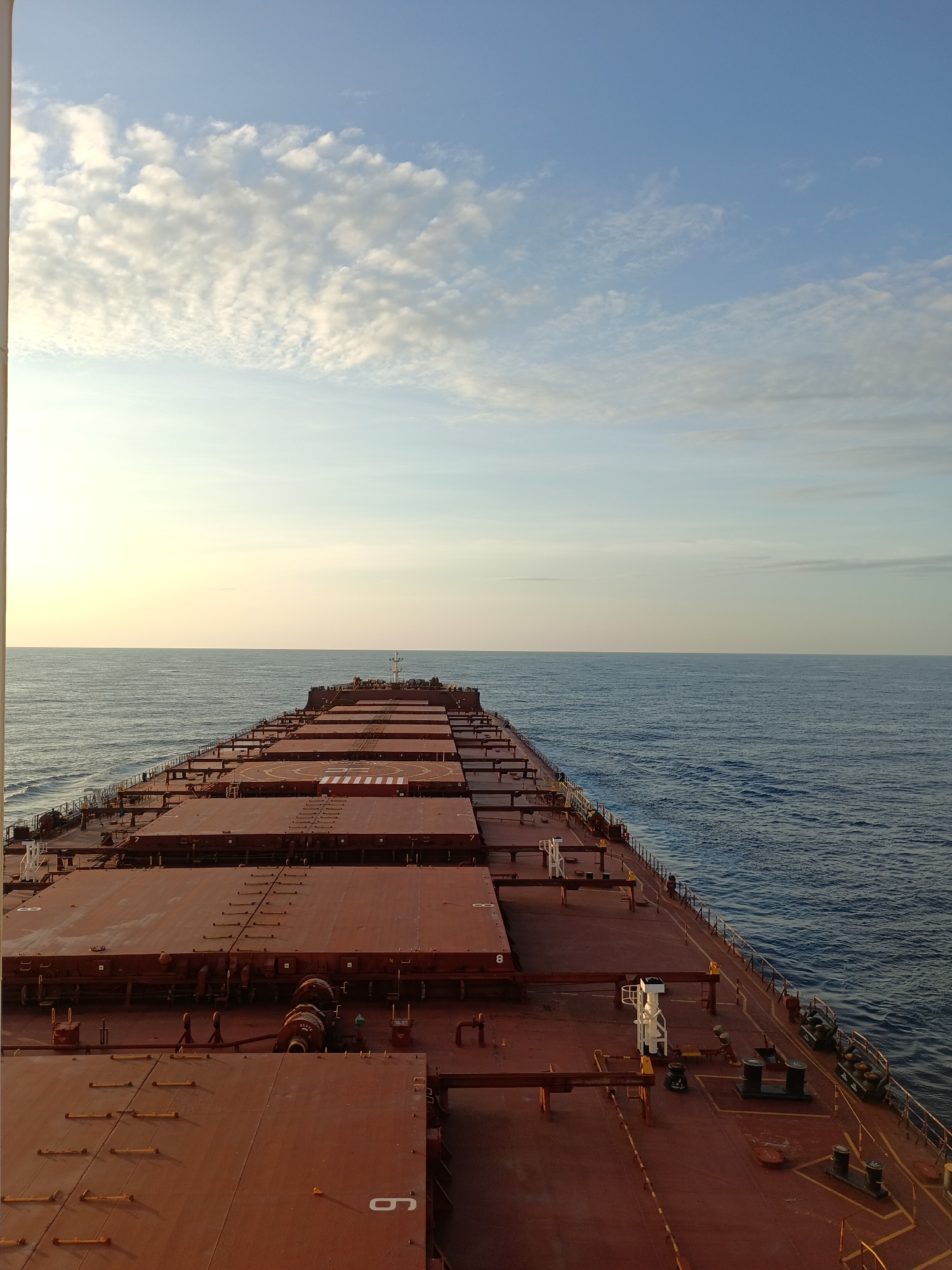 Cargo ship at sea during a calm ocean sunrise