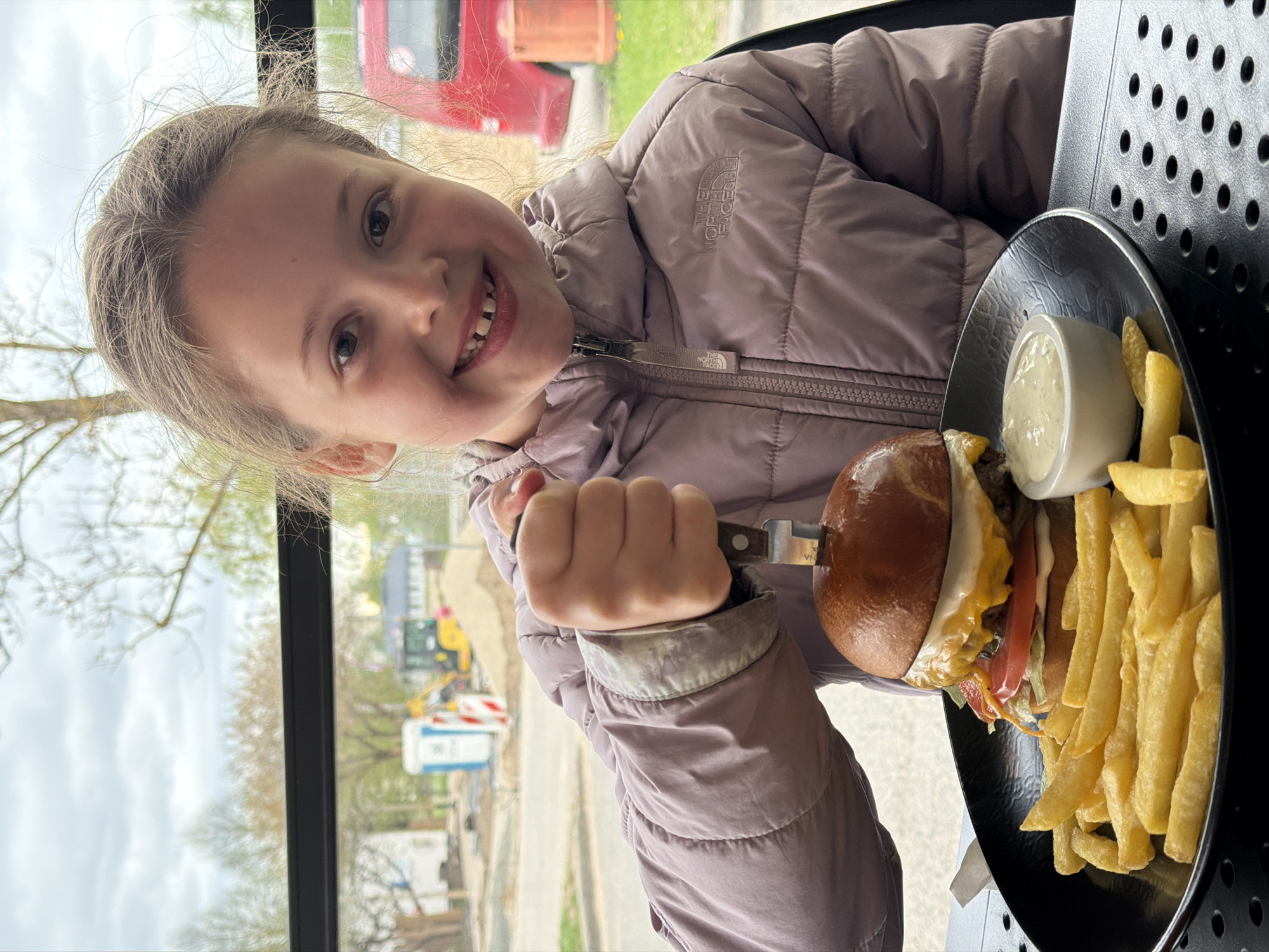 Girl enjoys hamburger lunch in Salaspils restaurant