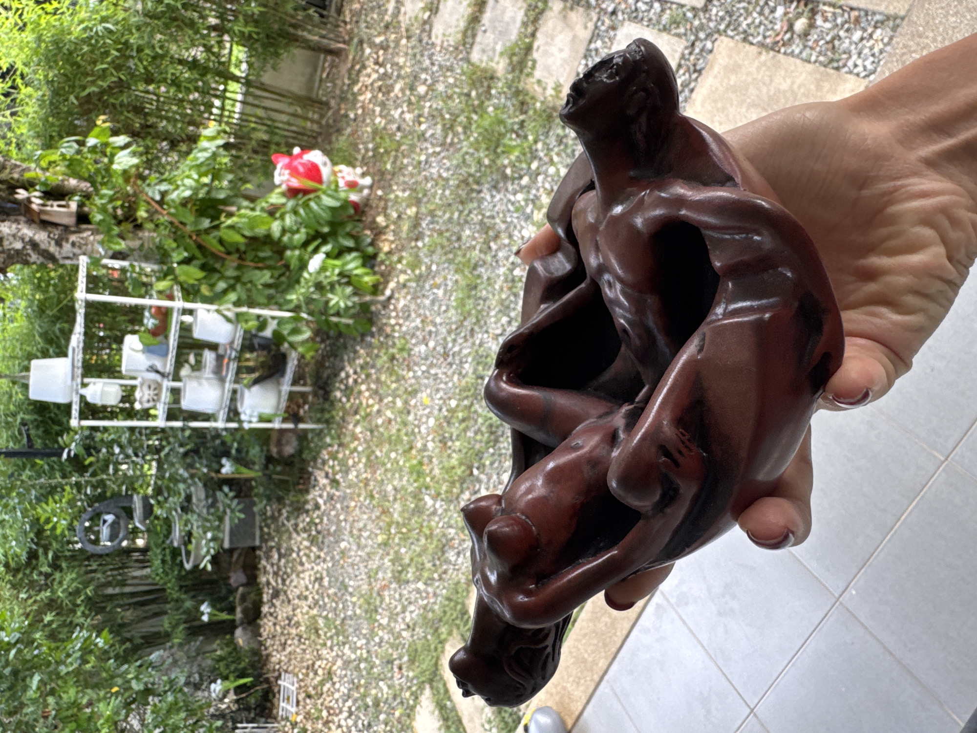 Wooden sculpture of entwined figures displayed in Chalong garden