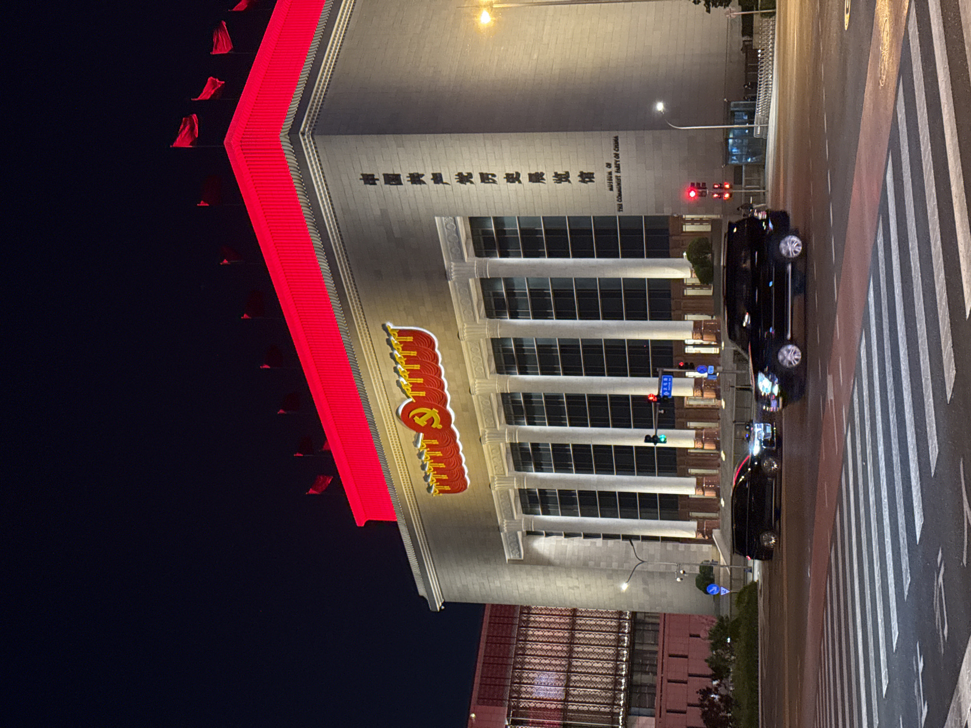 Pedestrian crosses street near illuminated Communist Party museum in Beijing