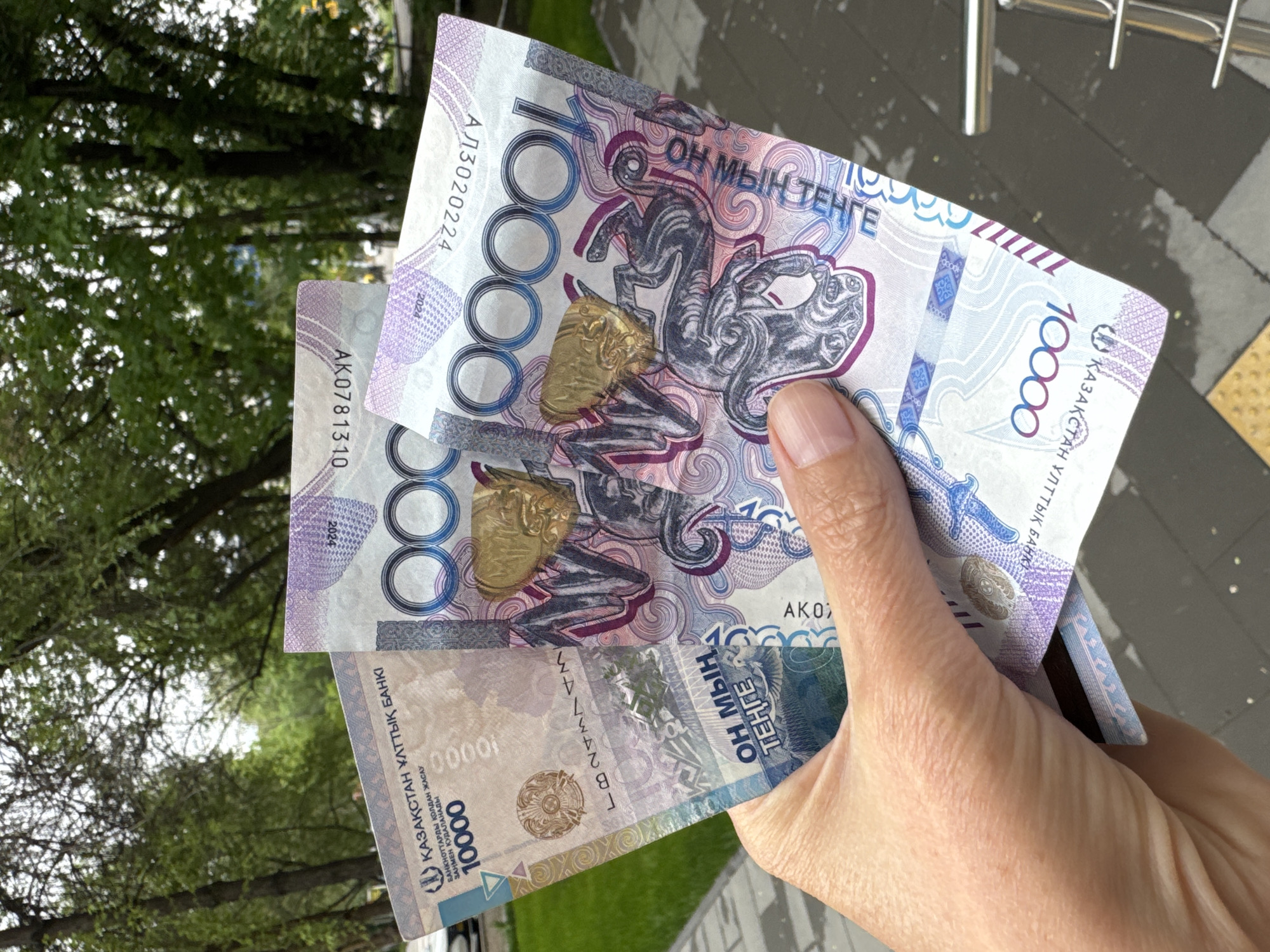 Person handles cash near automated terminal in Almaty