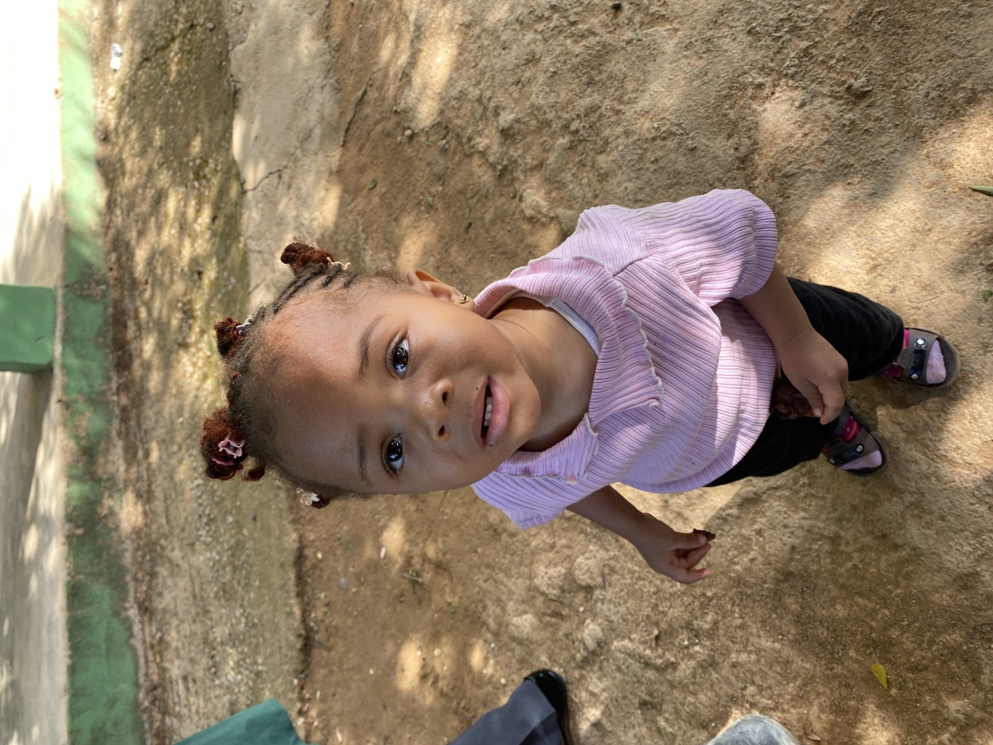 Toddler plays outdoors with caregiver in Nigerian community