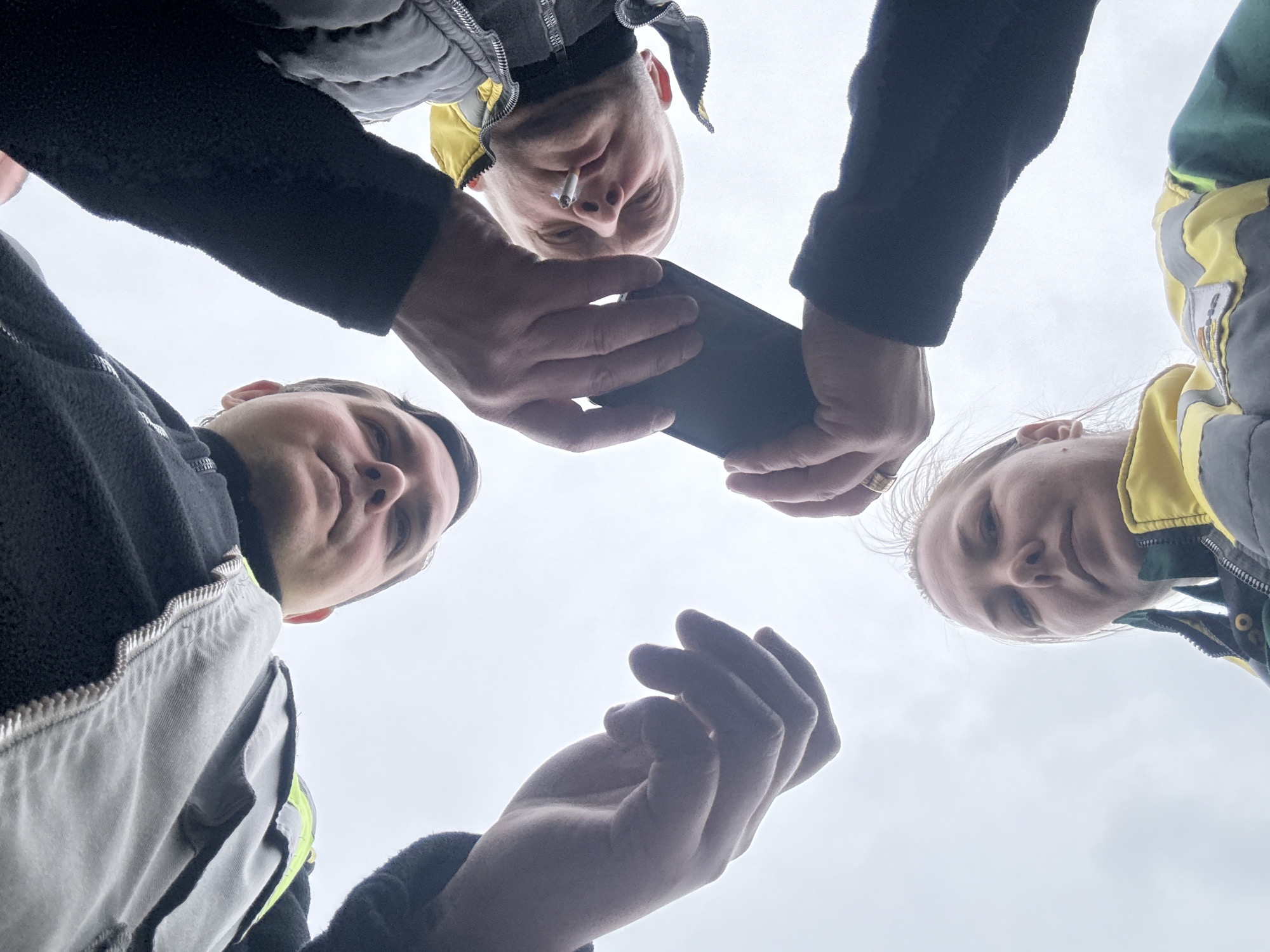 Four people gather in circle, one smoking, one filming