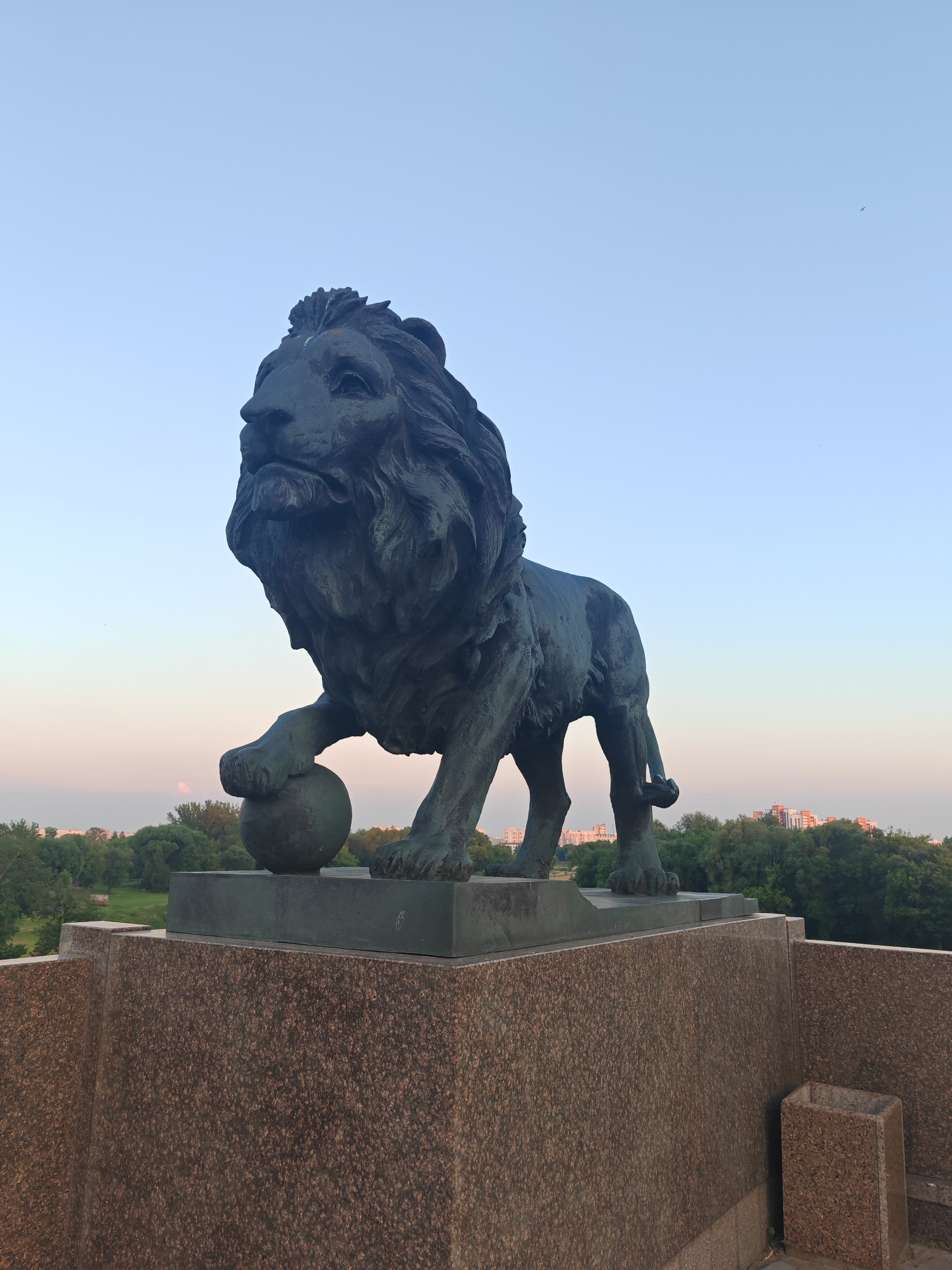 Bronze lion statue on pedestal at dusk, Mahilyow