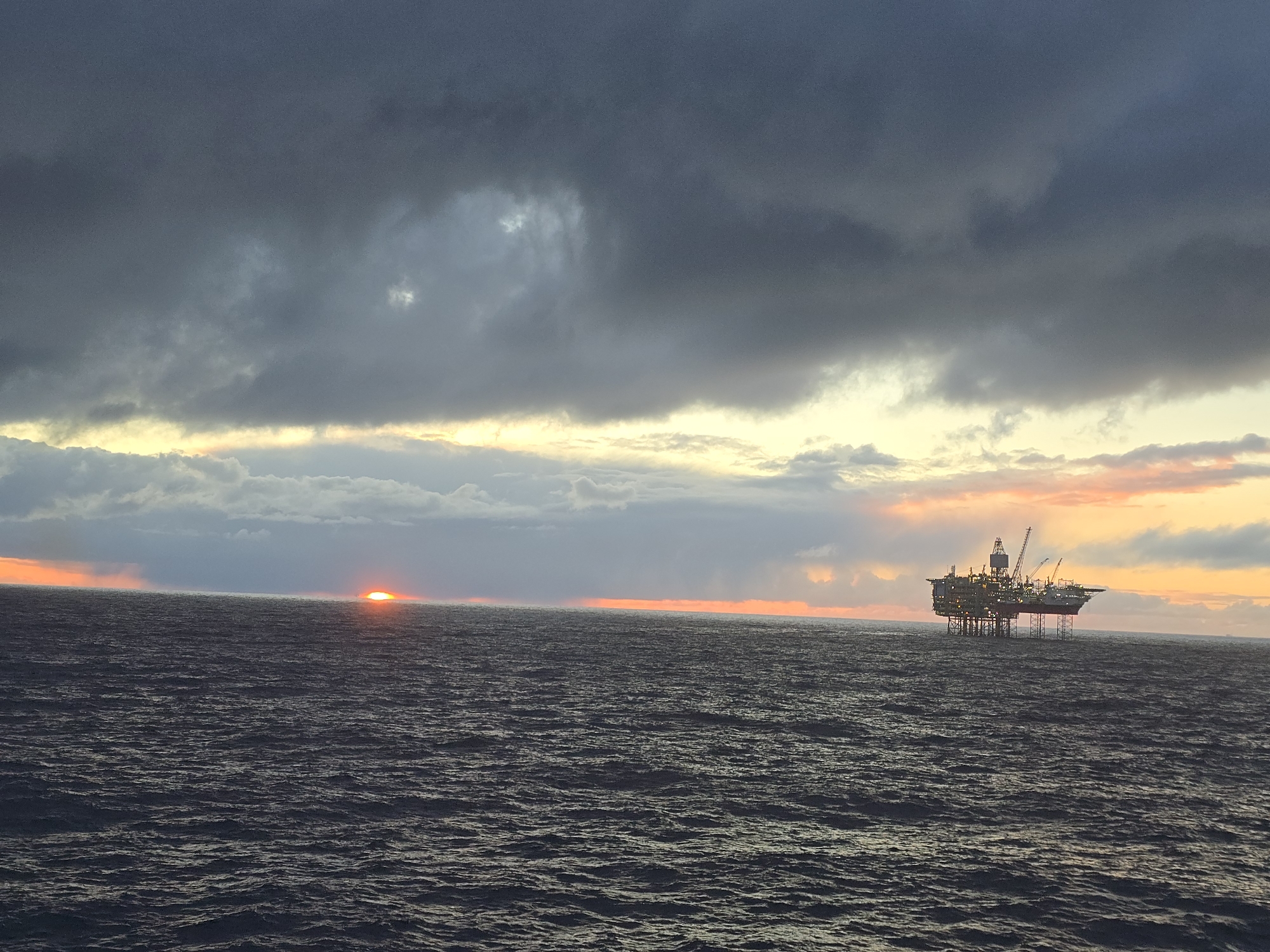 Offshore oil platform observed at dramatic sunset in North Sea