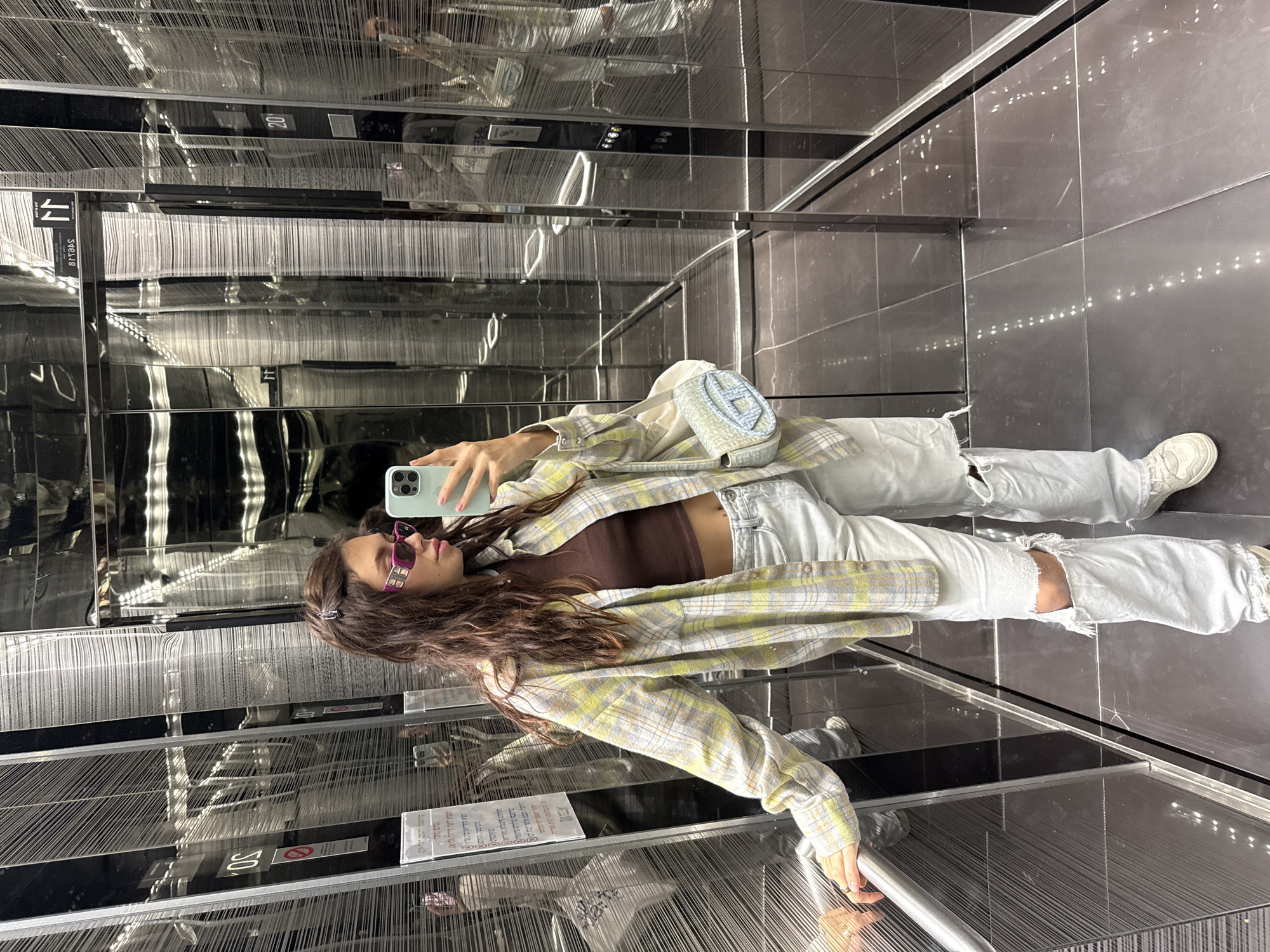 Woman takes elevator selfie in casual outfit