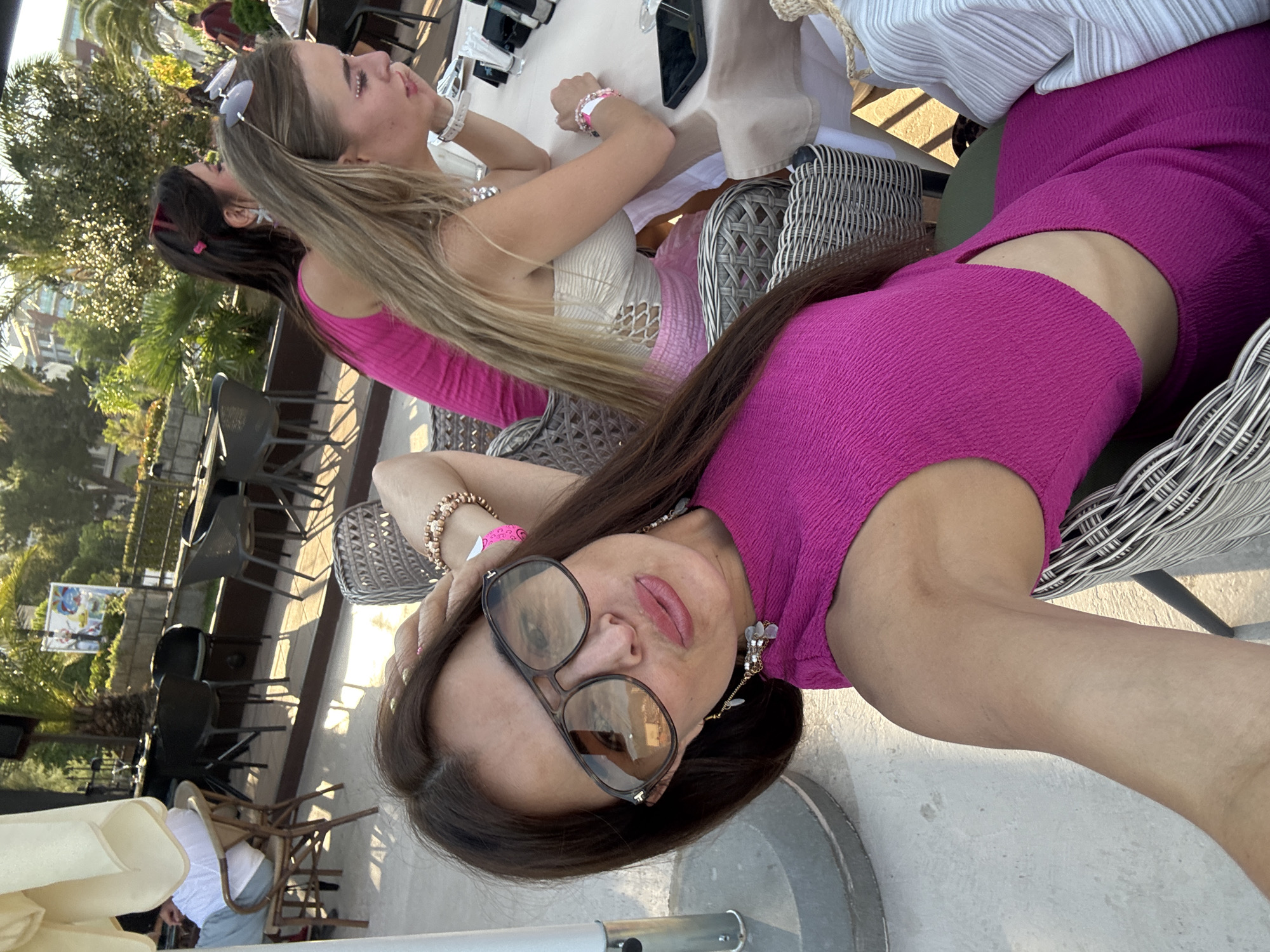 Bright pink outfit and aviator shades, posing outdoors