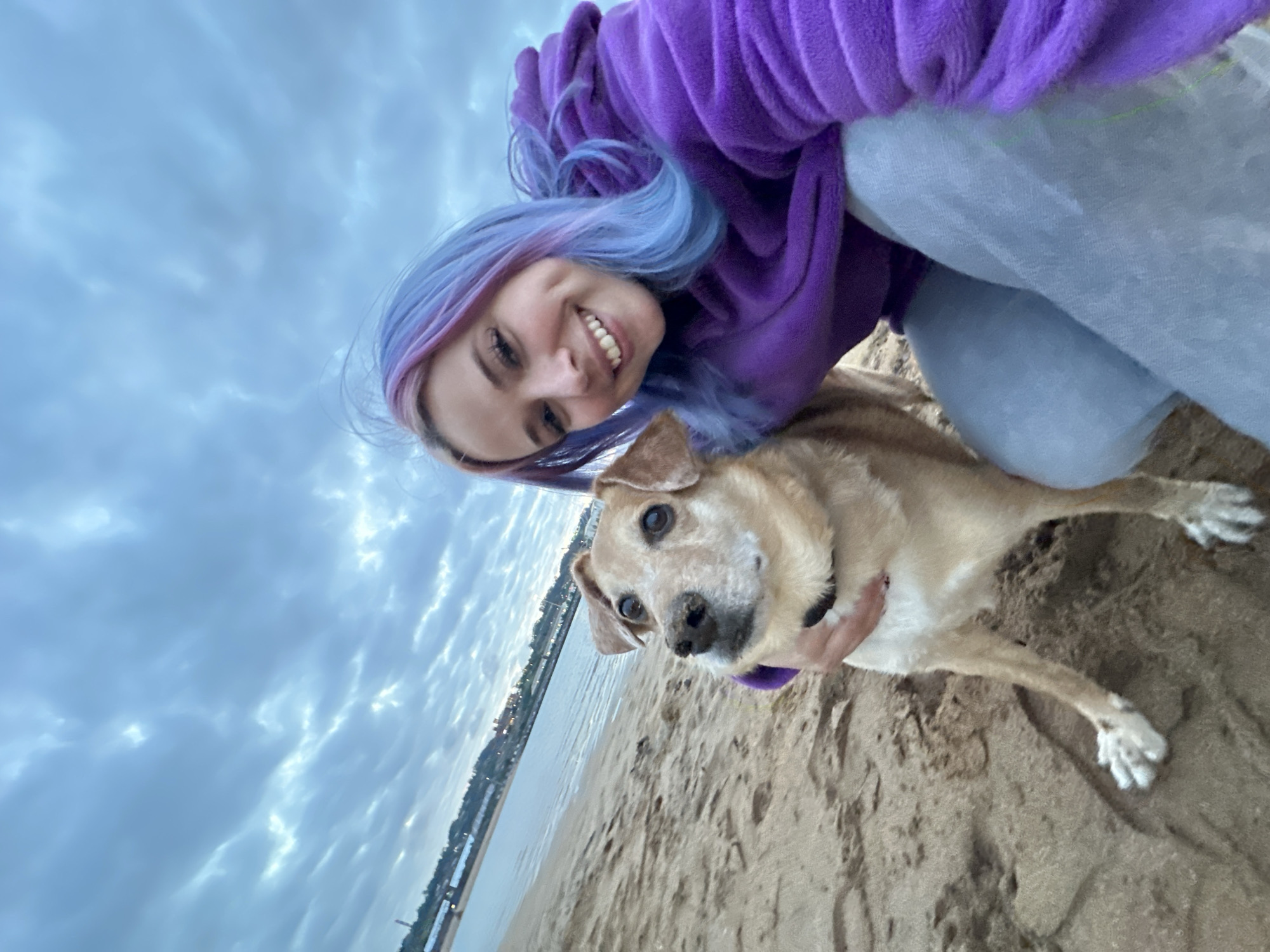 Woman and dog enjoy sunset playtime at Gijón beach