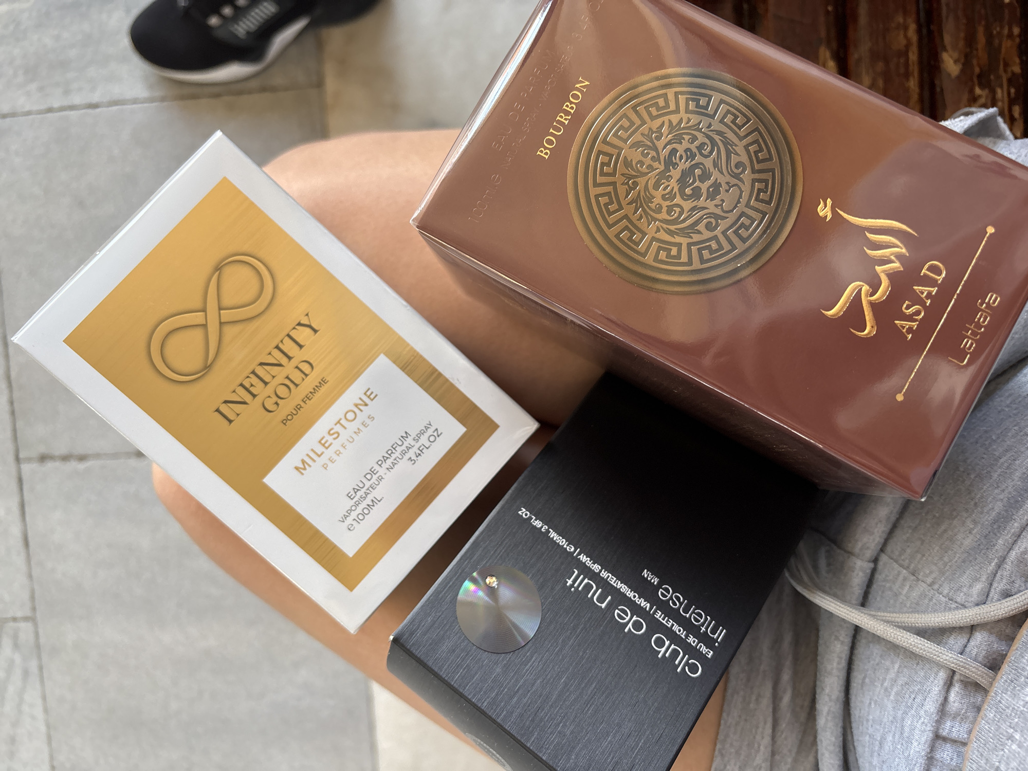 Person displays perfume collection while drinking energy drink