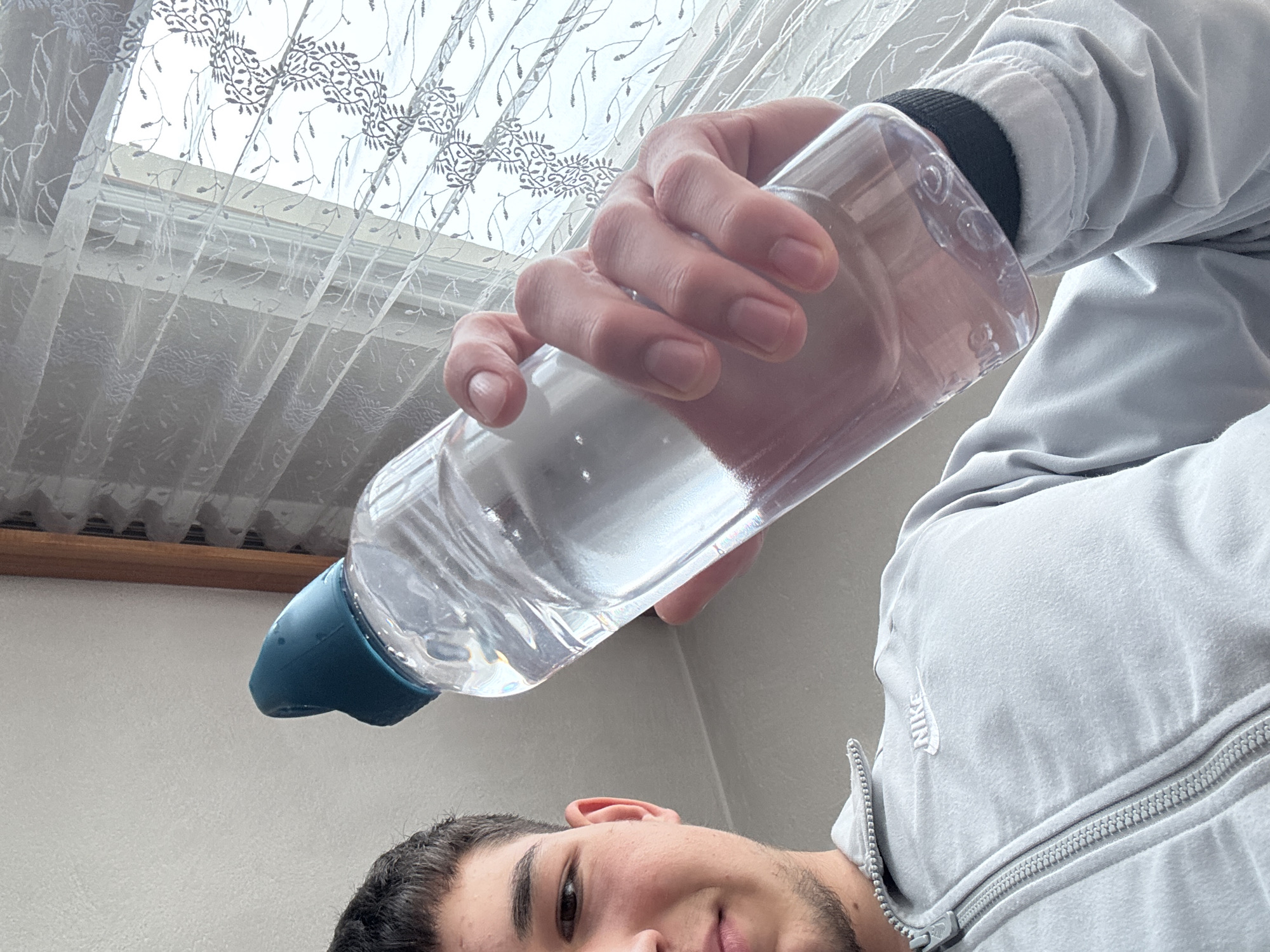 Young man photographed drinking water indoors in Zlatograd, Bulgaria
