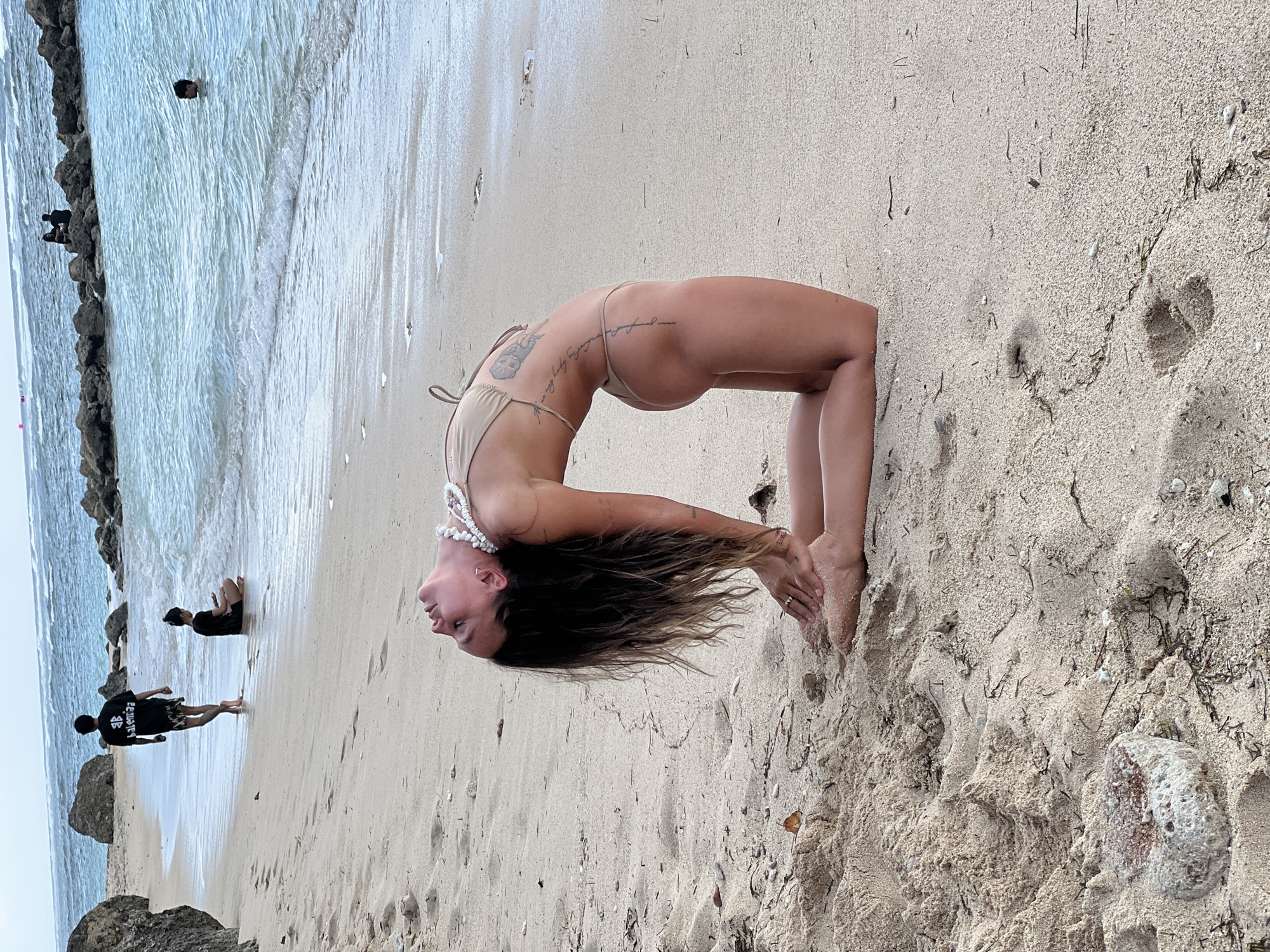 Woman performs yoga backbend on Kuta Selatan beach