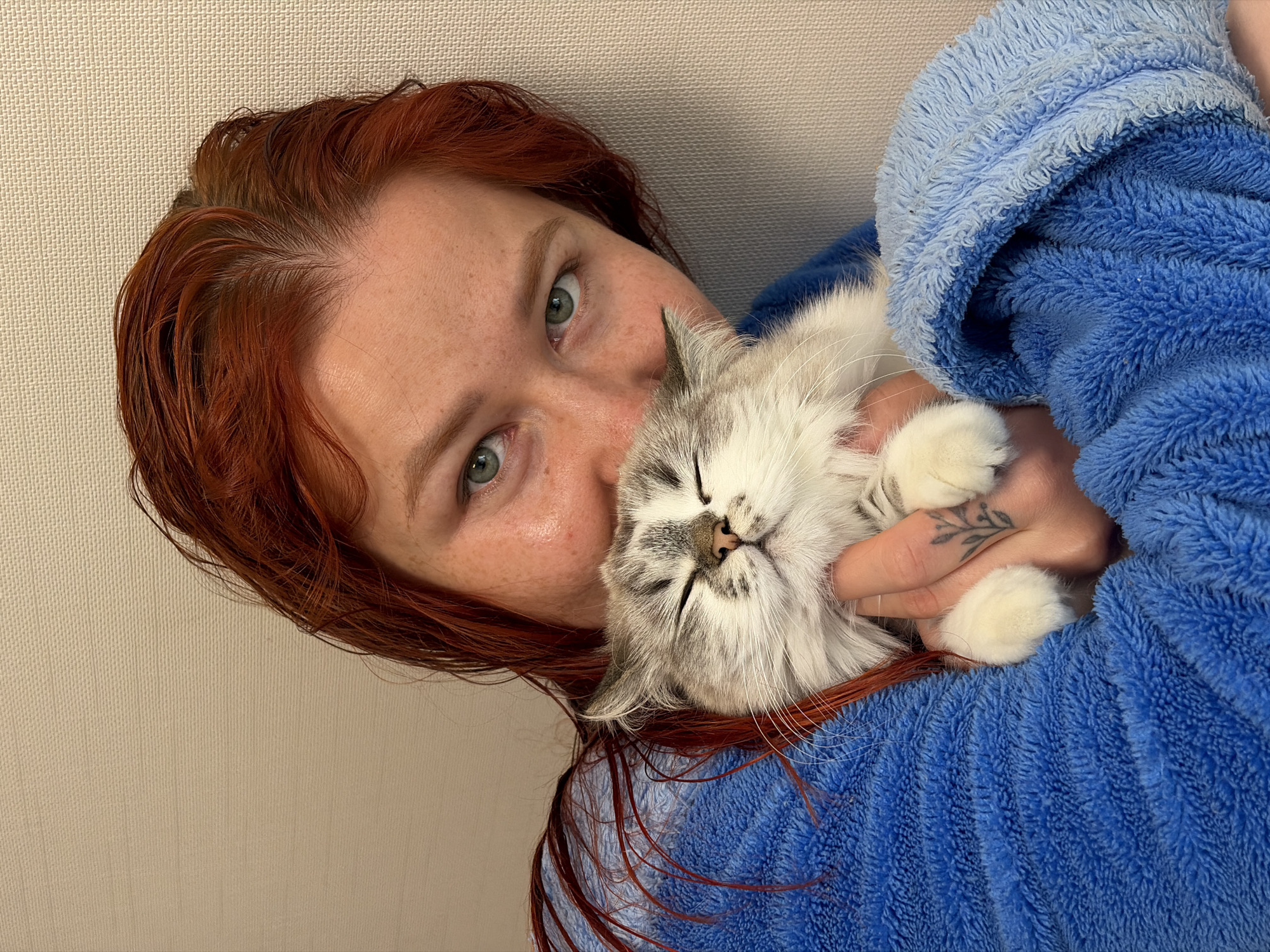 Woman in blue robe cuddles sleeping kitten in Rostov-on-Don