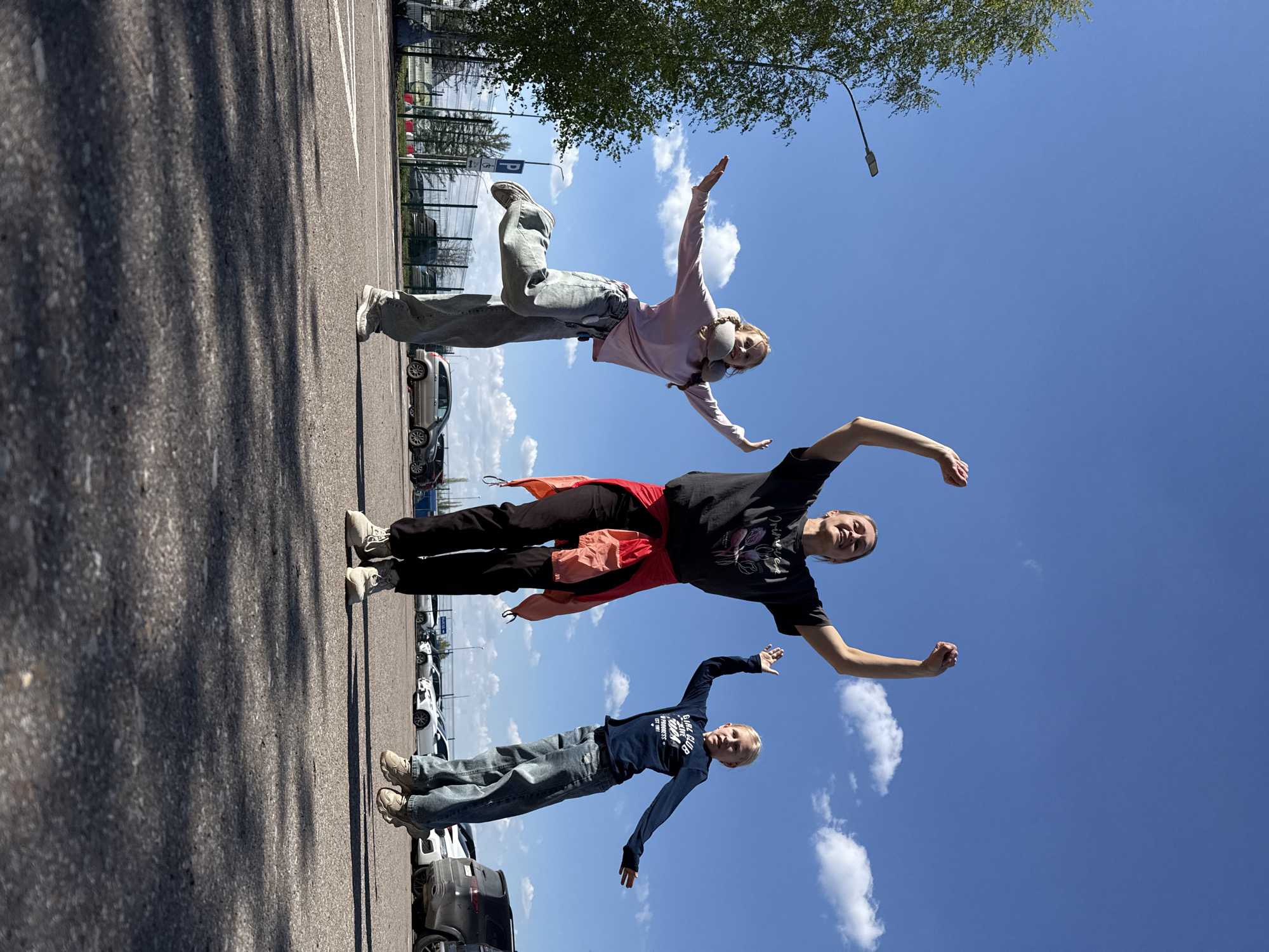 Three people pose and dance at Ufa Airport parking lot
