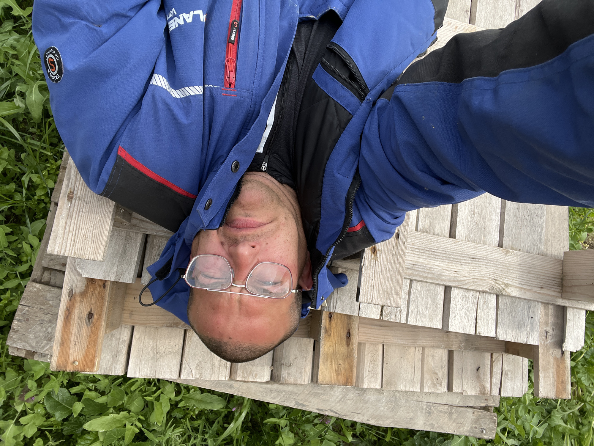 Man rests on wooden pallet outdoors in Topoli
