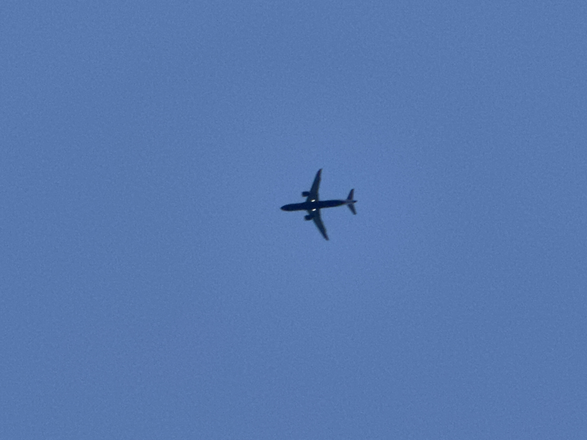 Planes and a crescent moon cross a clear London sky