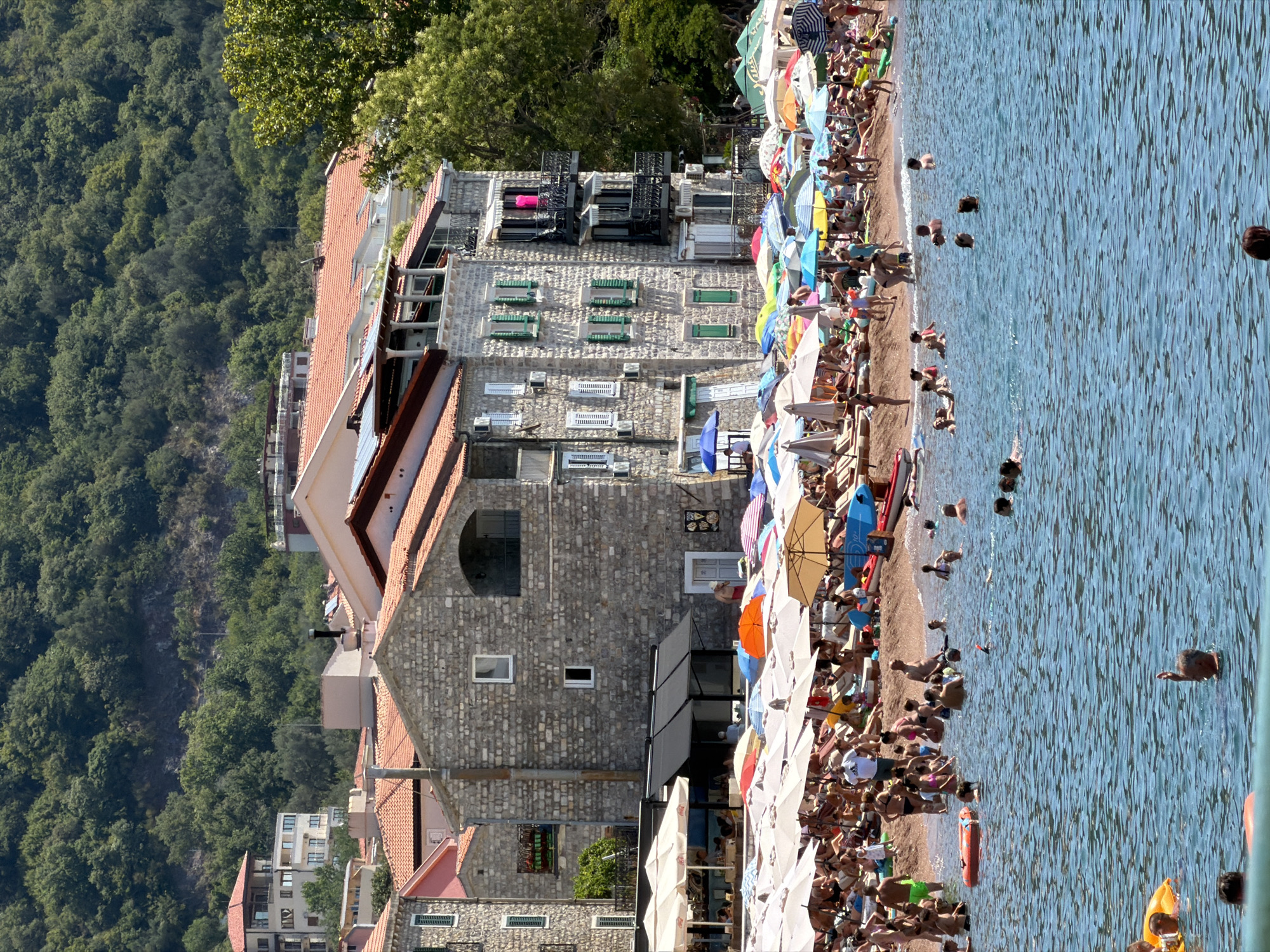 Sunny morning at Petrovac — beach, harbor boats, and café terrace