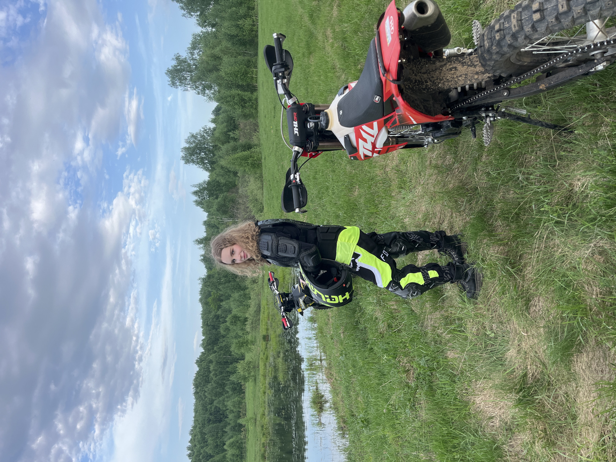 Motocross rider pauses by water with dirt bikes in Russia