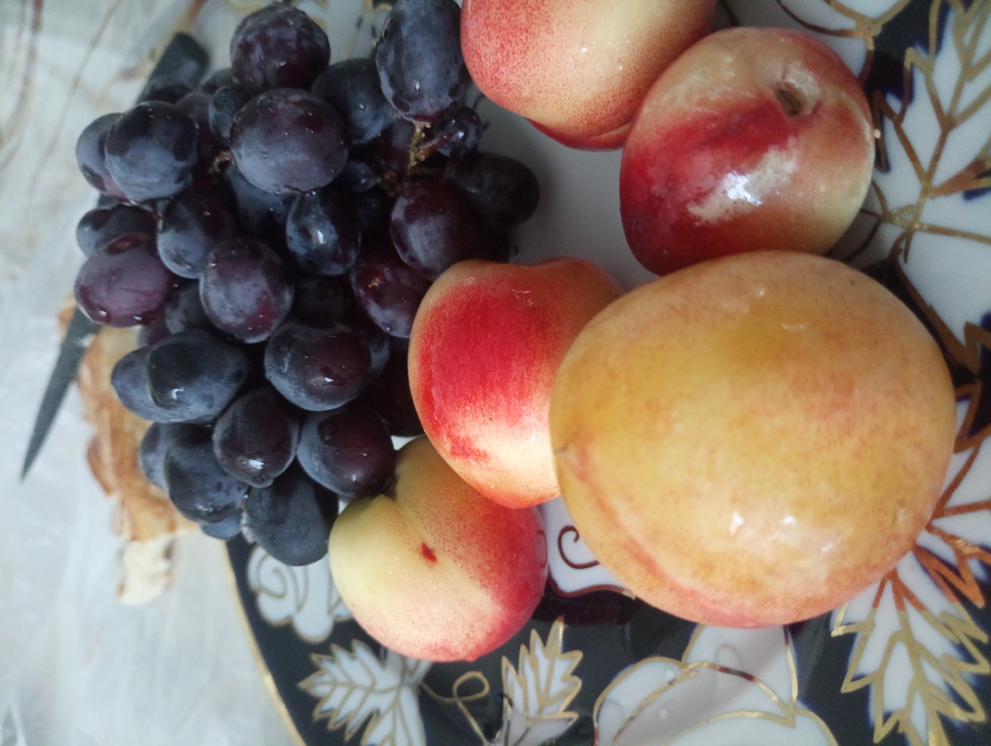 Fresh nectarines and bread on a decorative blue and gold plate