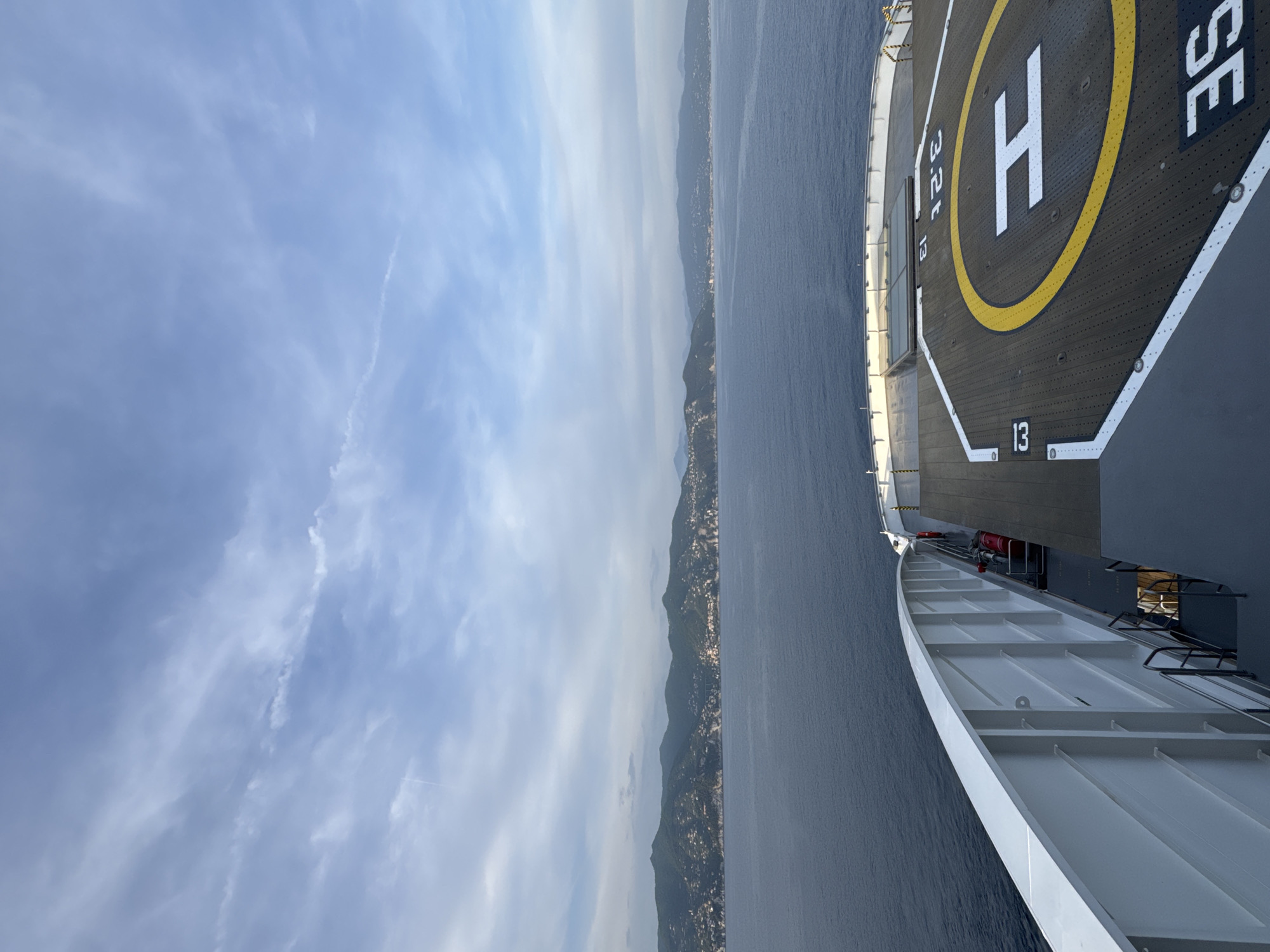 Ship passenger observes coastal mountains under cloudy skies