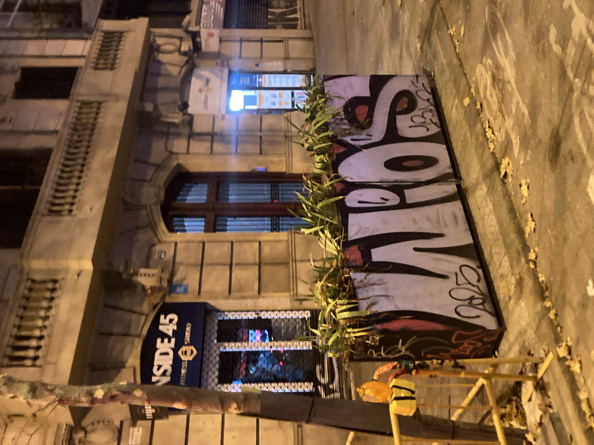 Barcelona street at night: shuttered shops, graffiti, and a lift platform